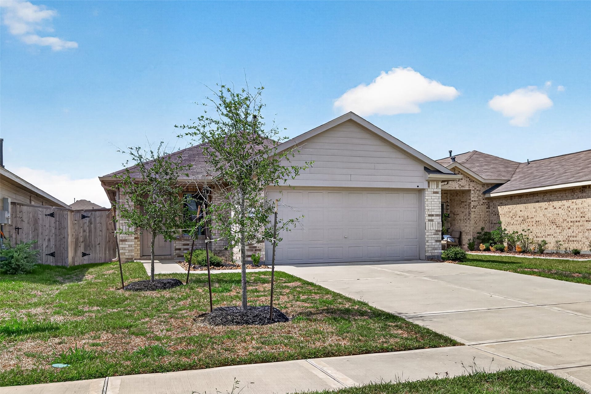 19494 Rosali Meadow Drive, New Caney, TX 77357 Enticing single-story home with a welcoming facade, featuring a spacious two-car garage and a neatly landscaped front yard with trees.