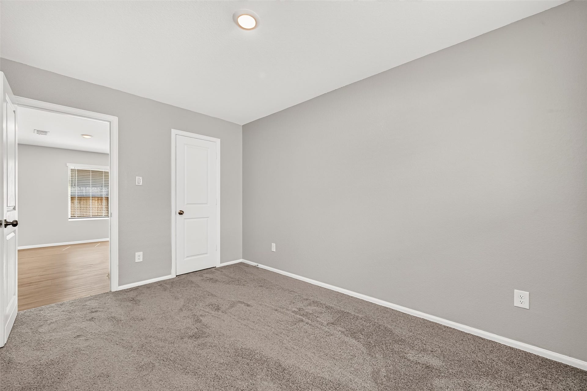 19494 Rosali Meadow Drive, New Caney, TX 77357 Cozy room with soft carpeting and neutral walls, featuring a bright, open doorway leading to a sunlit space.