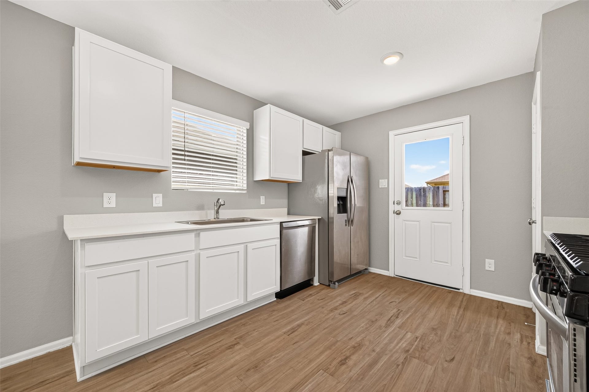 19494 Rosali Meadow Drive, New Caney, TX 77357 Bright kitchen with sleek stainless steel appliances, modern white cabinetry, and warm plank wood flooring, offering a welcoming and functional space.