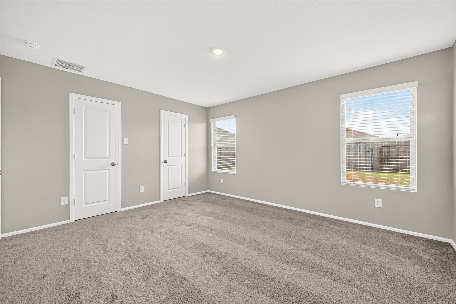 19494 Rosali Meadow Drive, New Caney, TX 77357 Spacious bedroom with soft carpet, neutral walls, and ample natural light from two large windows, offering a cozy and inviting atmosphere.
