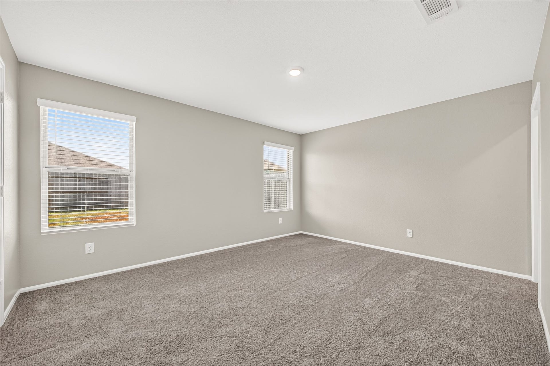 19494 Rosali Meadow Drive, New Caney, TX 77357 Newly carpeted primary bedroom with neutral walls and ample natural light from two large windows.