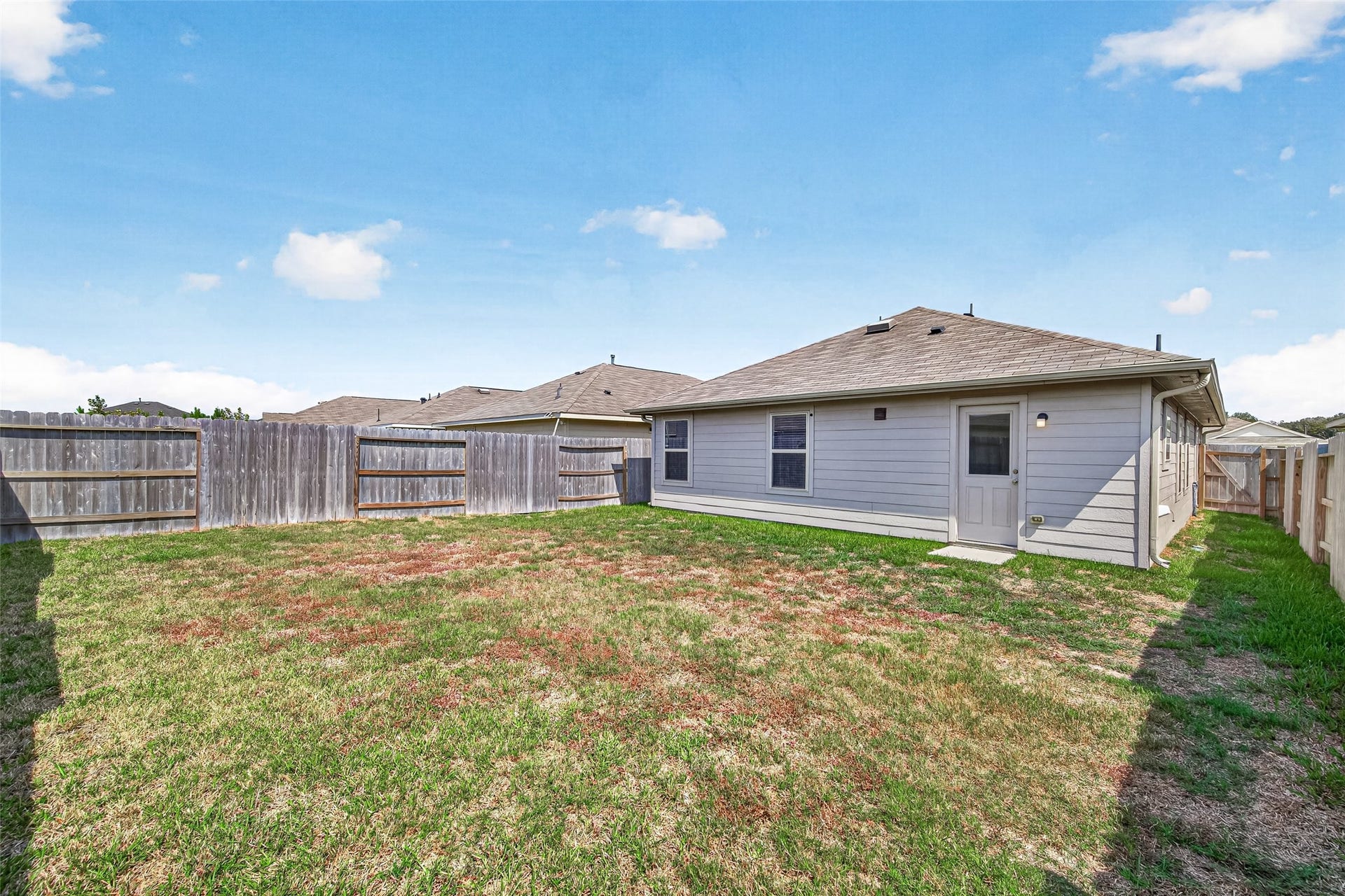19494 Rosali Meadow Drive, New Caney, TX 77357 Spacious backyard with privacy fencing and a well-maintained lawn, perfect for outdoor activities and relaxation.
