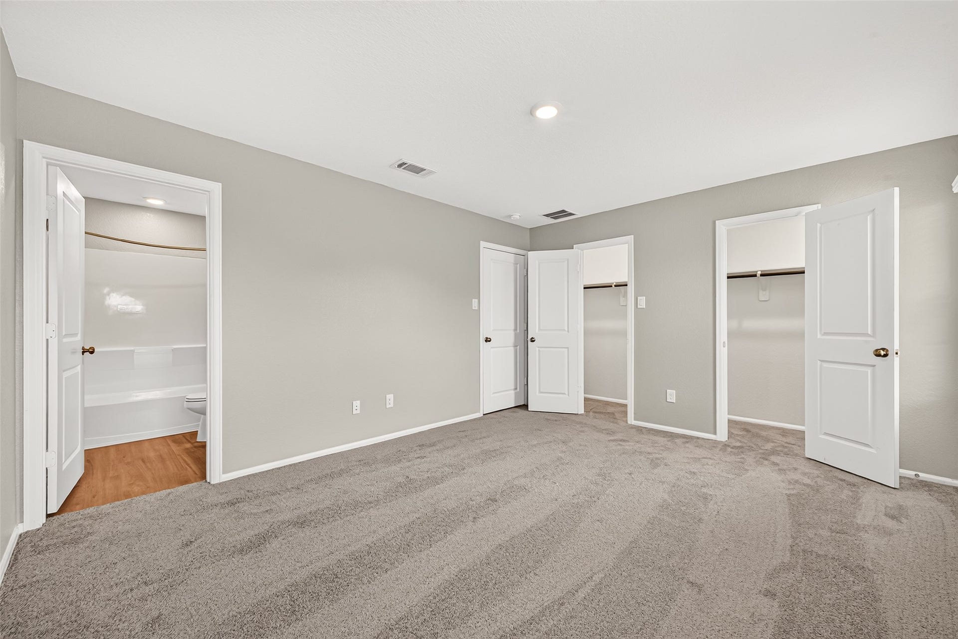 19494 Rosali Meadow Drive, New Caney, TX 77357 Spacious bedroom featuring new plush carpet, neutral walls, two walk-in closets, and an en-suite bathroom with a modern tub and sleek finishes.