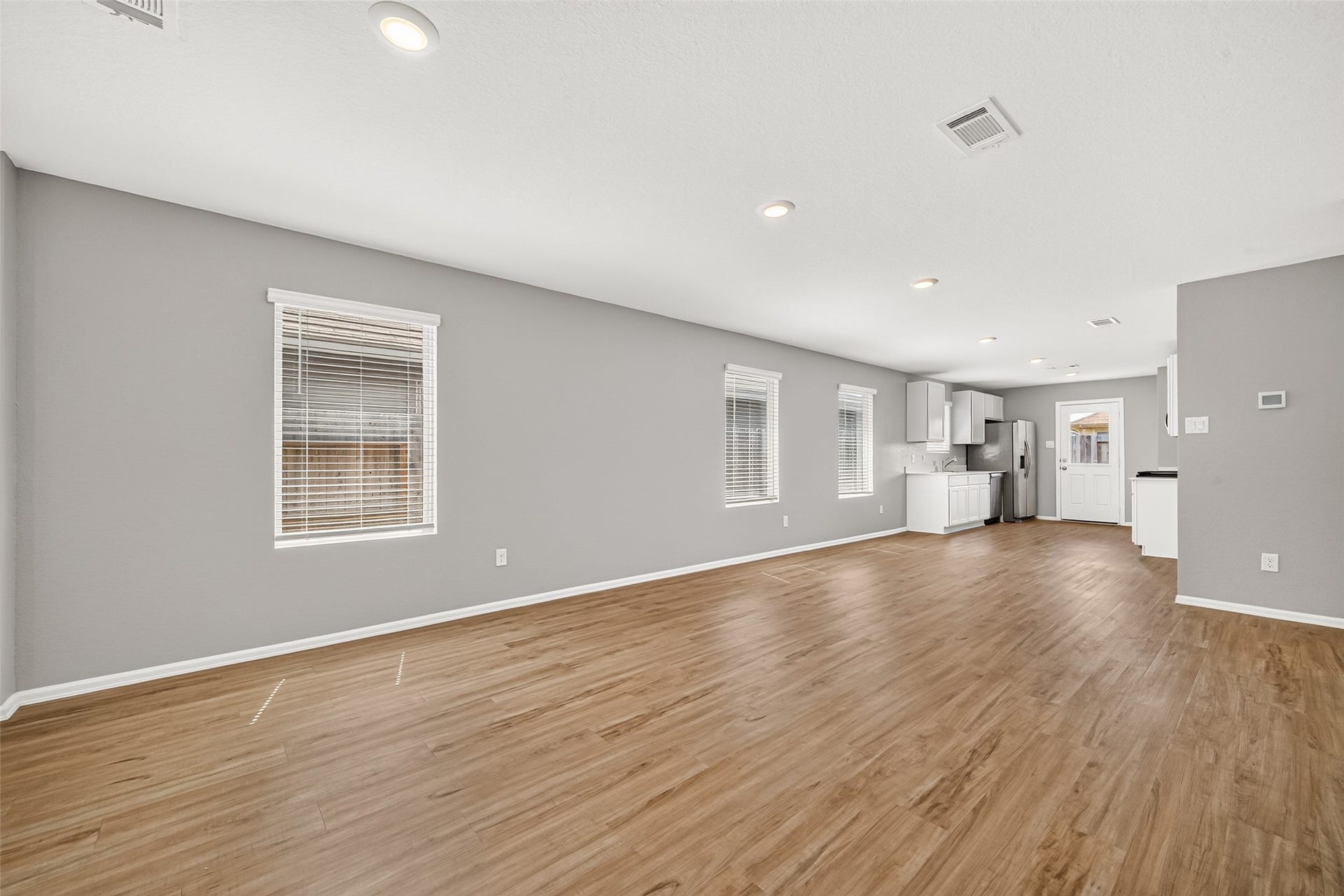 19494 Rosali Meadow Drive, New Caney, TX 77357 Spacious open-concept living area with sleek wood flooring, abundant natural light, and a modern kitchen featuring stainless steel appliances.