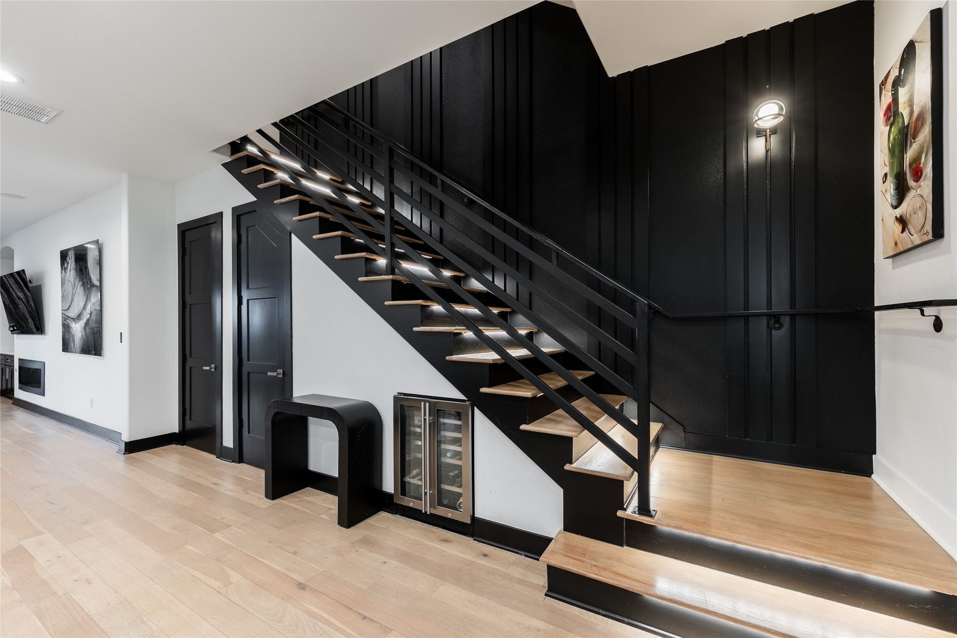 906 Knox Street, Houston, TX 77007 A dramatic paneled accent wall frames the illuminated staircase, while built-in wine storage beneath the stairs makes thoughtful use of the space without sacrificing design.