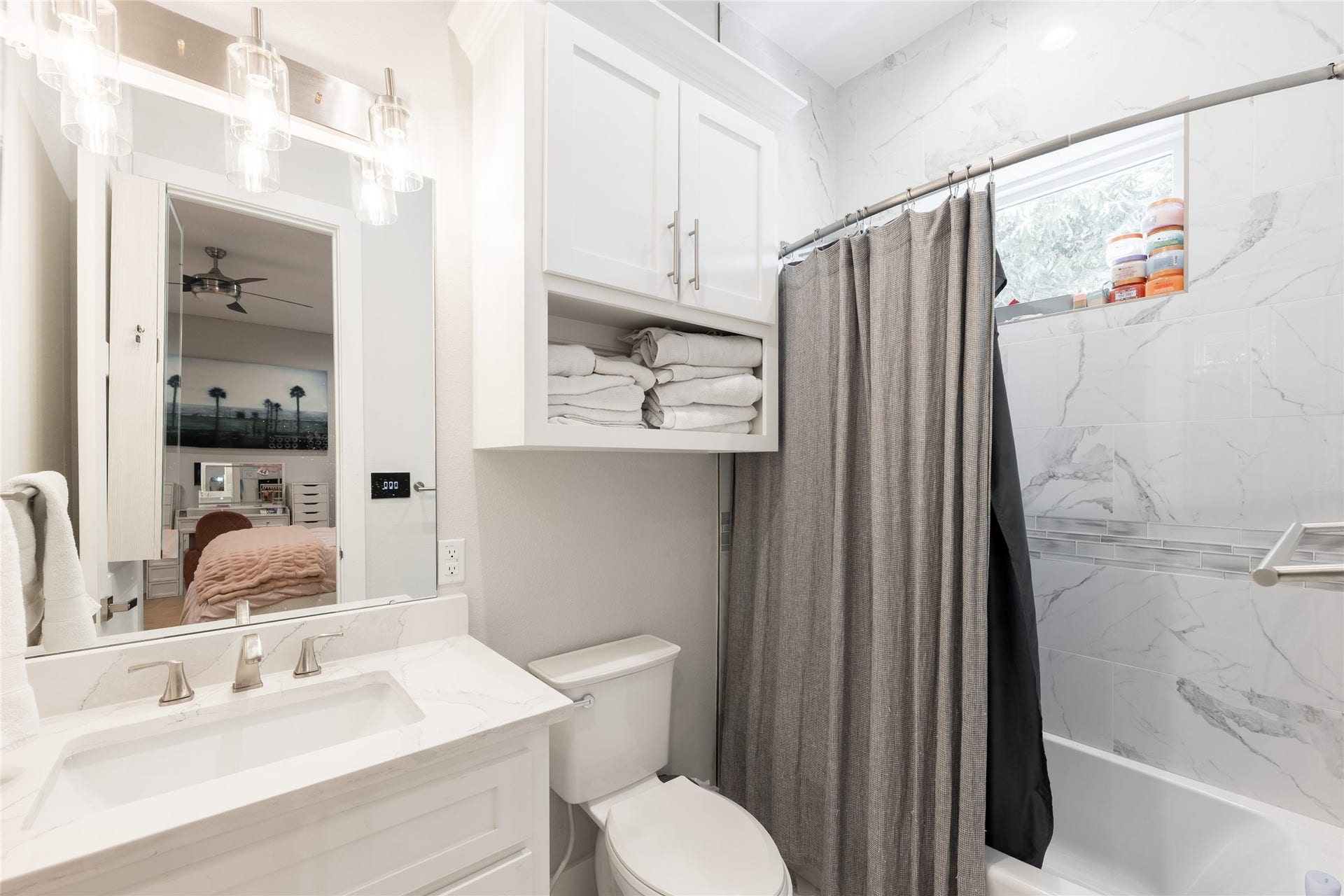 906 Knox Street, Houston, TX 77007 A well-finished ensuite gives the secondary bedroom its own sense of completeness, pairing a bright neutral palette with thoughtful storage and a tiled tub surround.