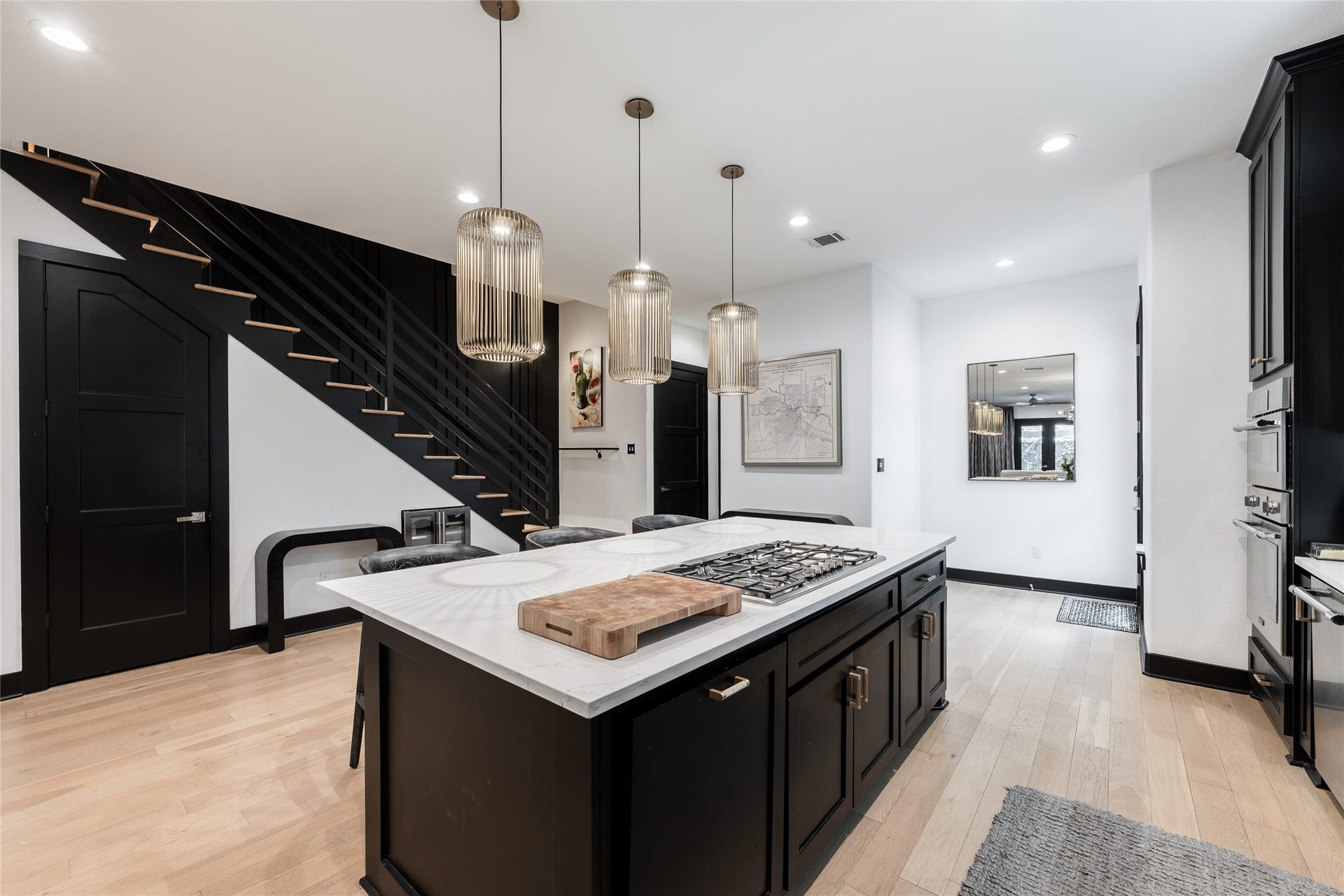 906 Knox Street, Houston, TX 77007 Designed to be both functional and visually striking, the substantial center island incorporates the cooktop, generous workspace and seating beneath a trio of statement pendants.