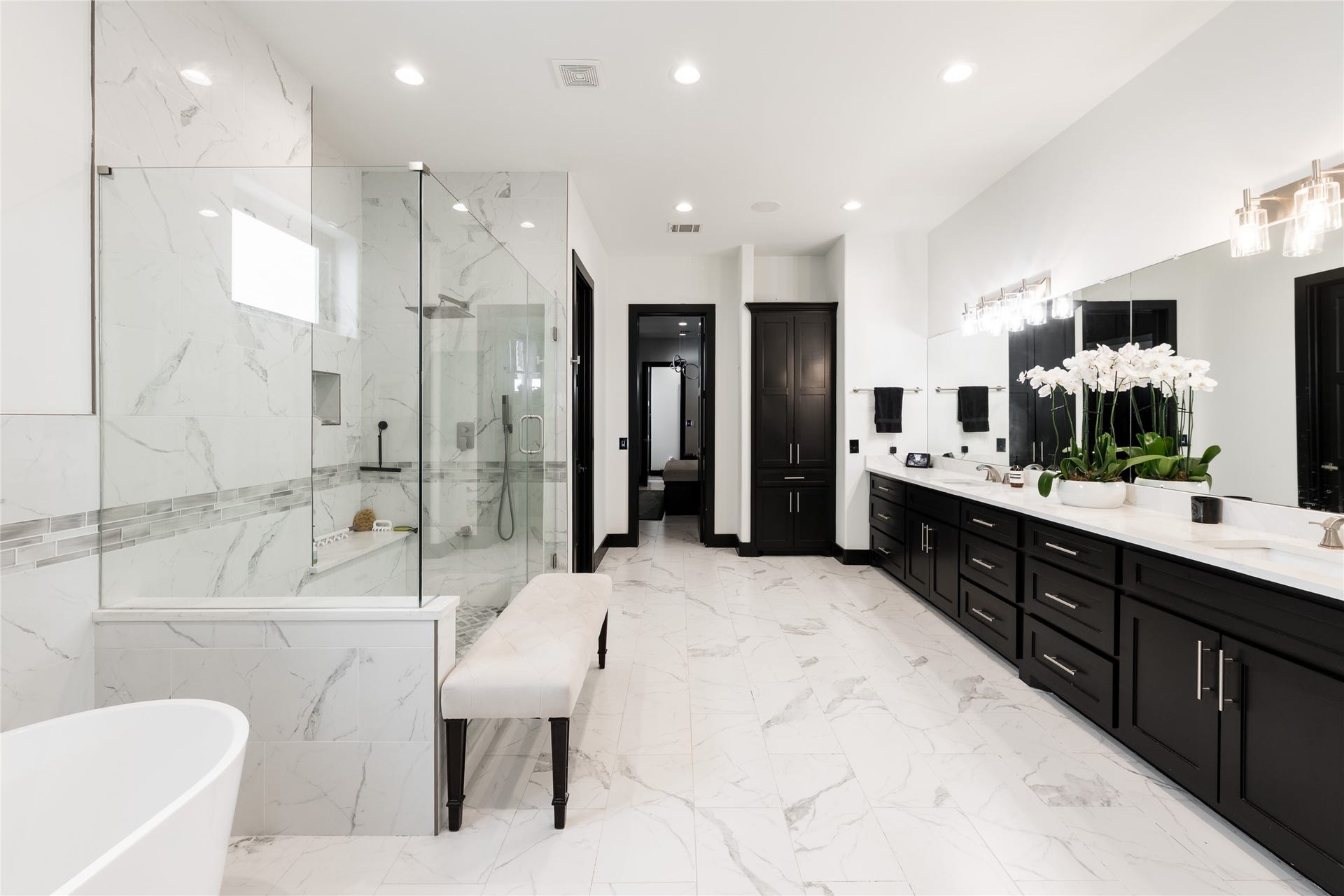 906 Knox Street, Houston, TX 77007 The primary bath continues with a glass-enclosed walk-in shower, freestanding soaking tub, expansive dual vanity, and extensive storage, all finished in a crisp black-and-white palette.