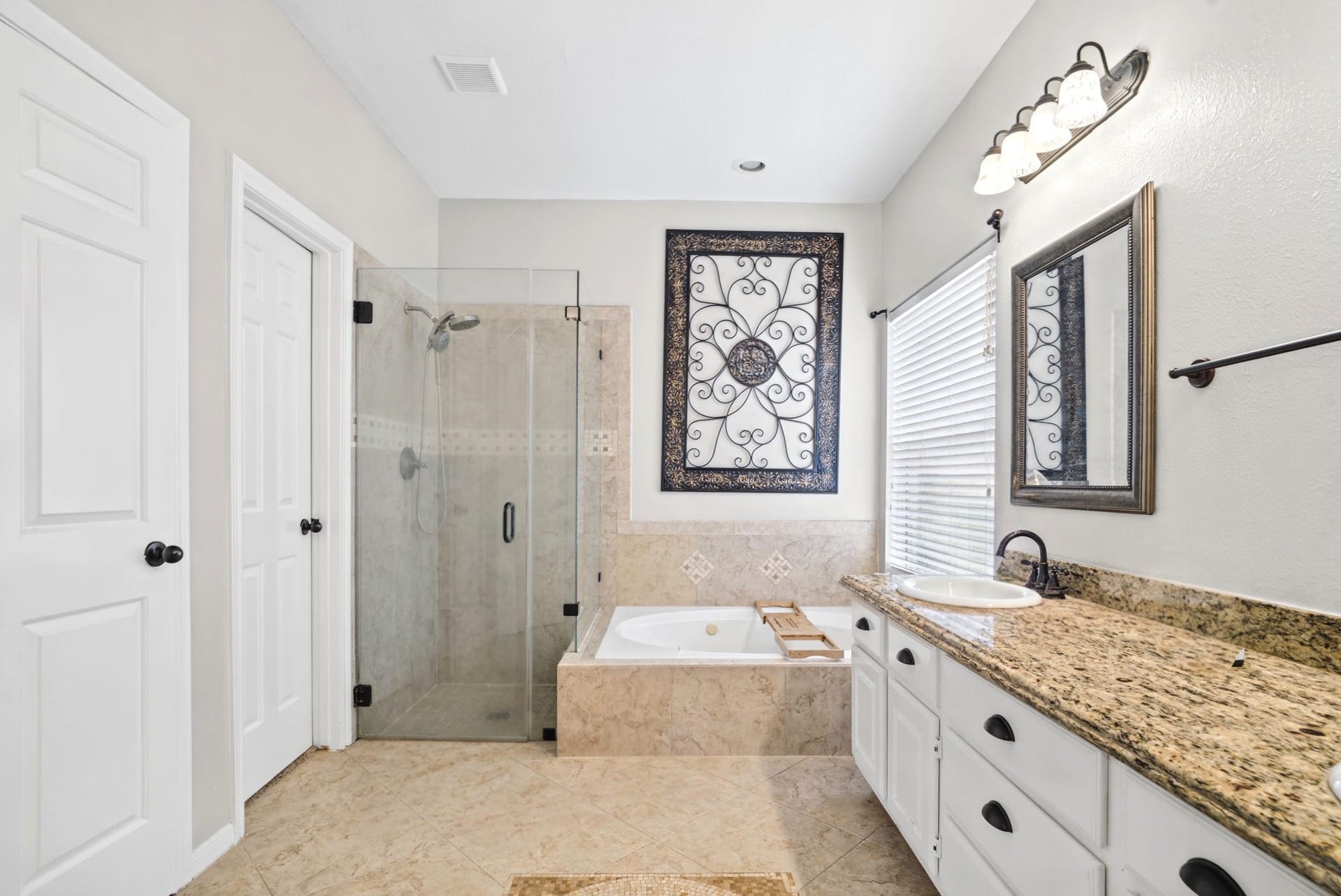 The primary bathroom features elegant white cabinetry, granite countertops, and a dual-sink vanity for added convenience. Unwind in the relaxing soaking tub or enjoy the separate walk-in shower. A window provides beautiful natural light, creating a bright and inviting space to start and end your day.