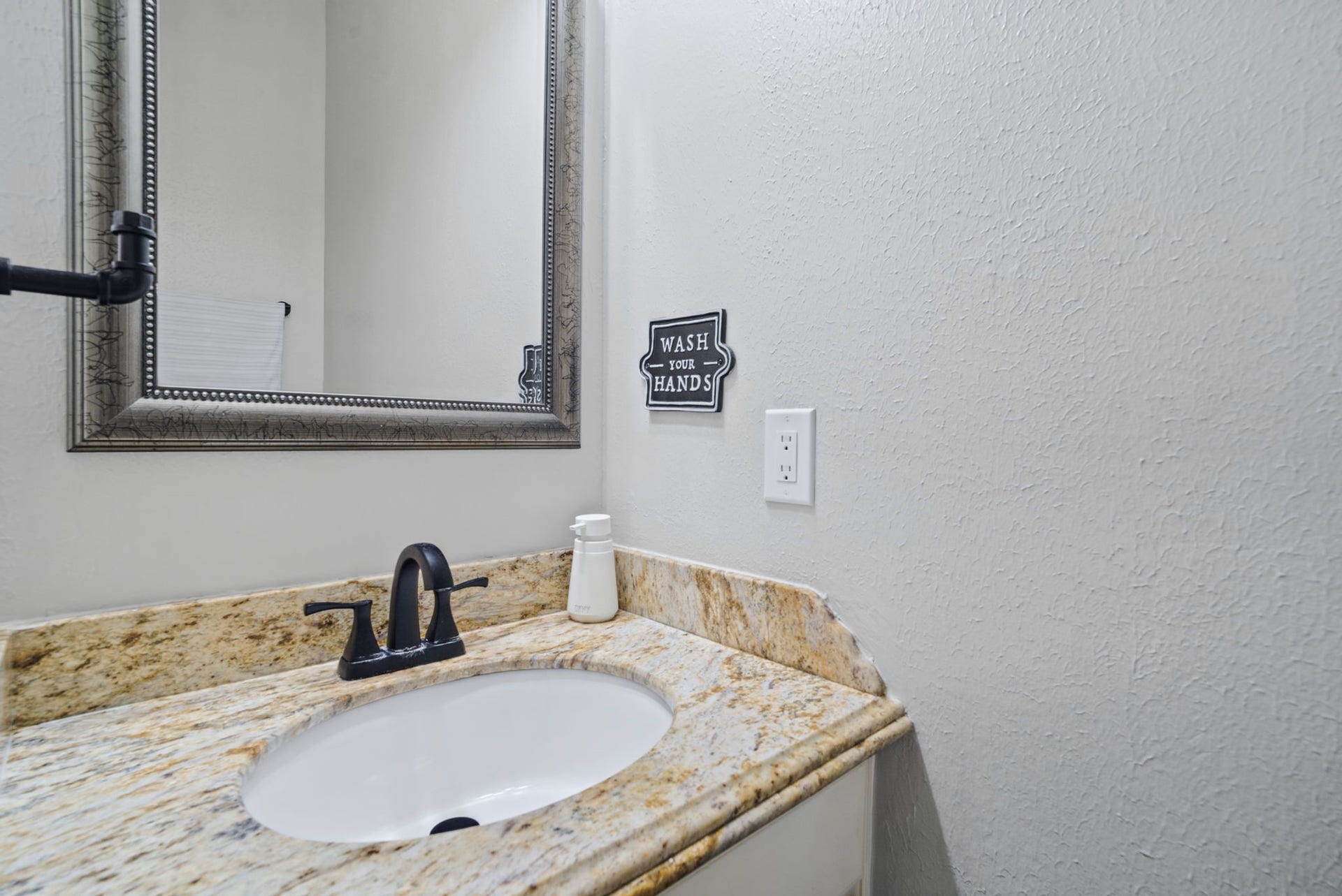 A convenient half bath is located just off the living room, featuring an elegant granite countertop and white cabinetry. Perfectly situated for guests, this stylish and functional space adds comfort and convenience when entertaining.