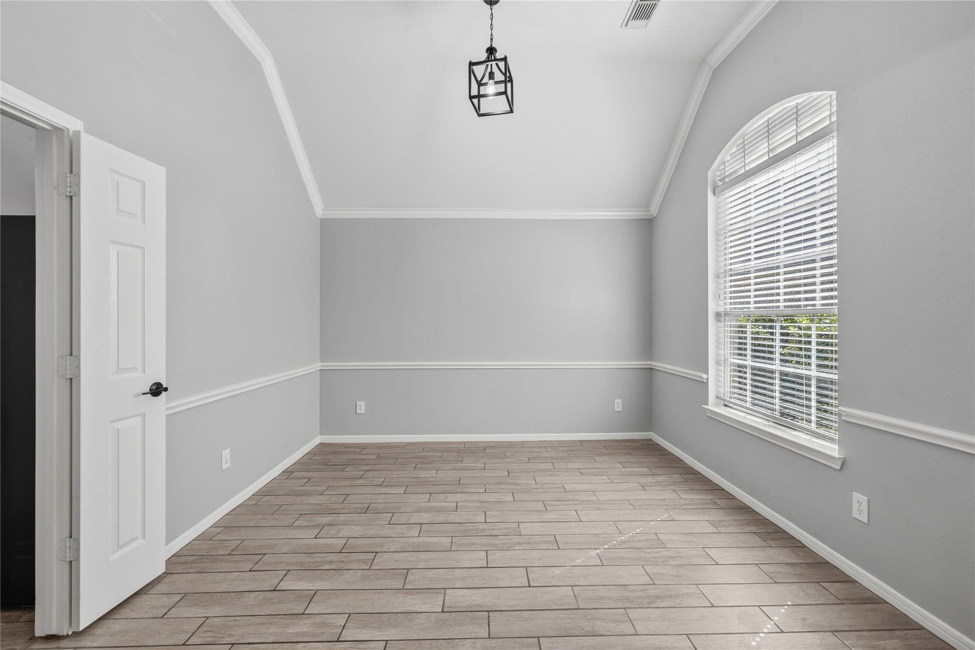 4011 Grayson Court, Missouri City, TX 77459 Bright and airy dining room featuring high vaulted ceilings, large arched window with blinds, and elegant wood-look tile flooring, offering a versatile space for any purpose.