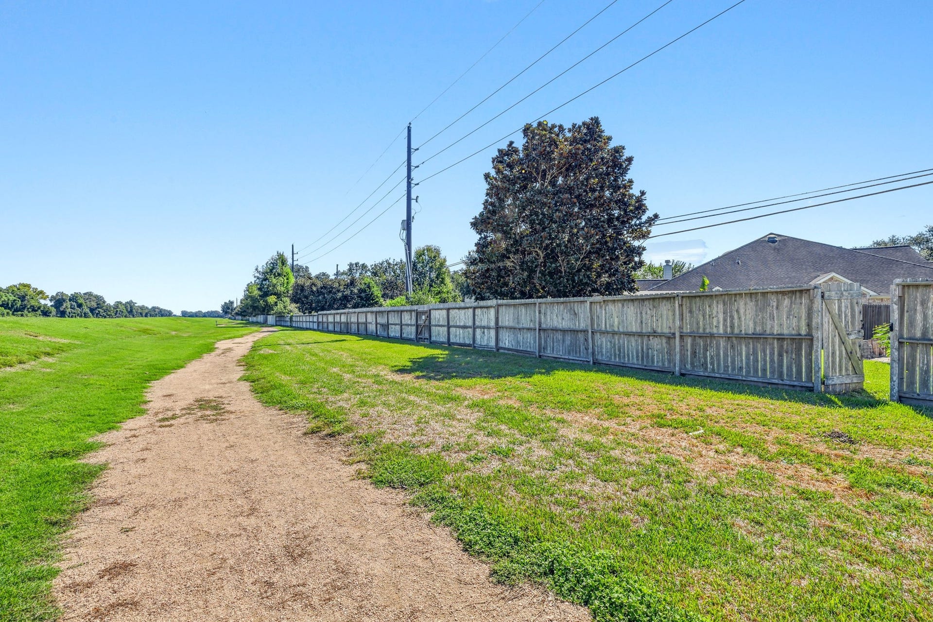 4011 Grayson Court, Missouri City, TX 77459 Expansive green space with a walking trail adjacent to a fenced backyard, offering a serene setting for outdoor activities.