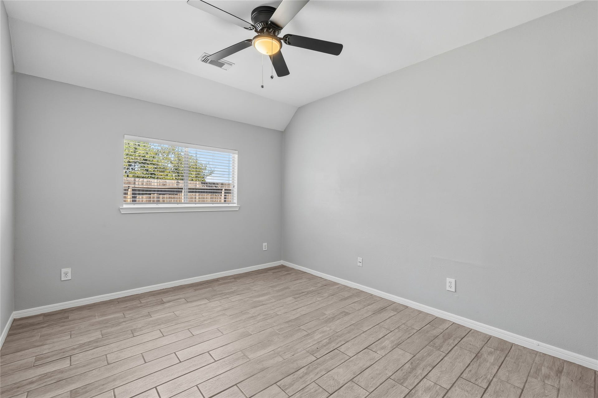 4011 Grayson Court, Missouri City, TX 77459 Bright and airy bedroom featuring sleek wood-look tile flooring, a modern ceiling fan, and a large window for natural light.