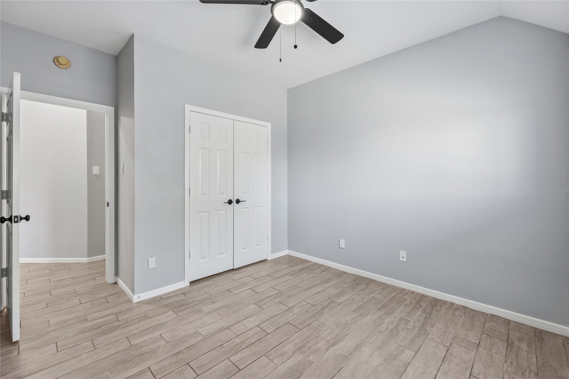4011 Grayson Court, Missouri City, TX 77459 Bright room with a modern ceiling fan, neutral gray walls, and wood-look tile flooring, offering a clean and versatile space.