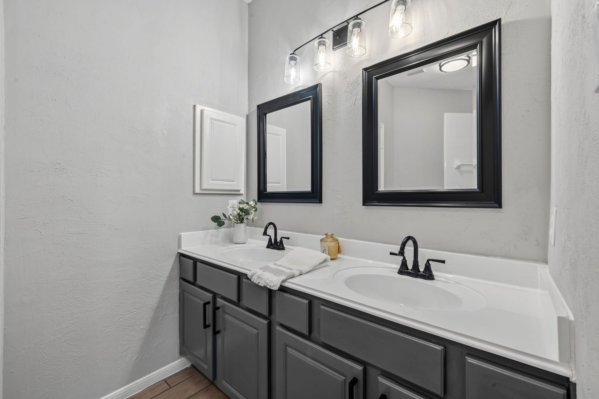 4011 Grayson Court, Missouri City, TX 77459 Modern bathroom featuring a stylish double vanity with sleek black fixtures, framed mirrors, and ample storage in dark cabinetry.