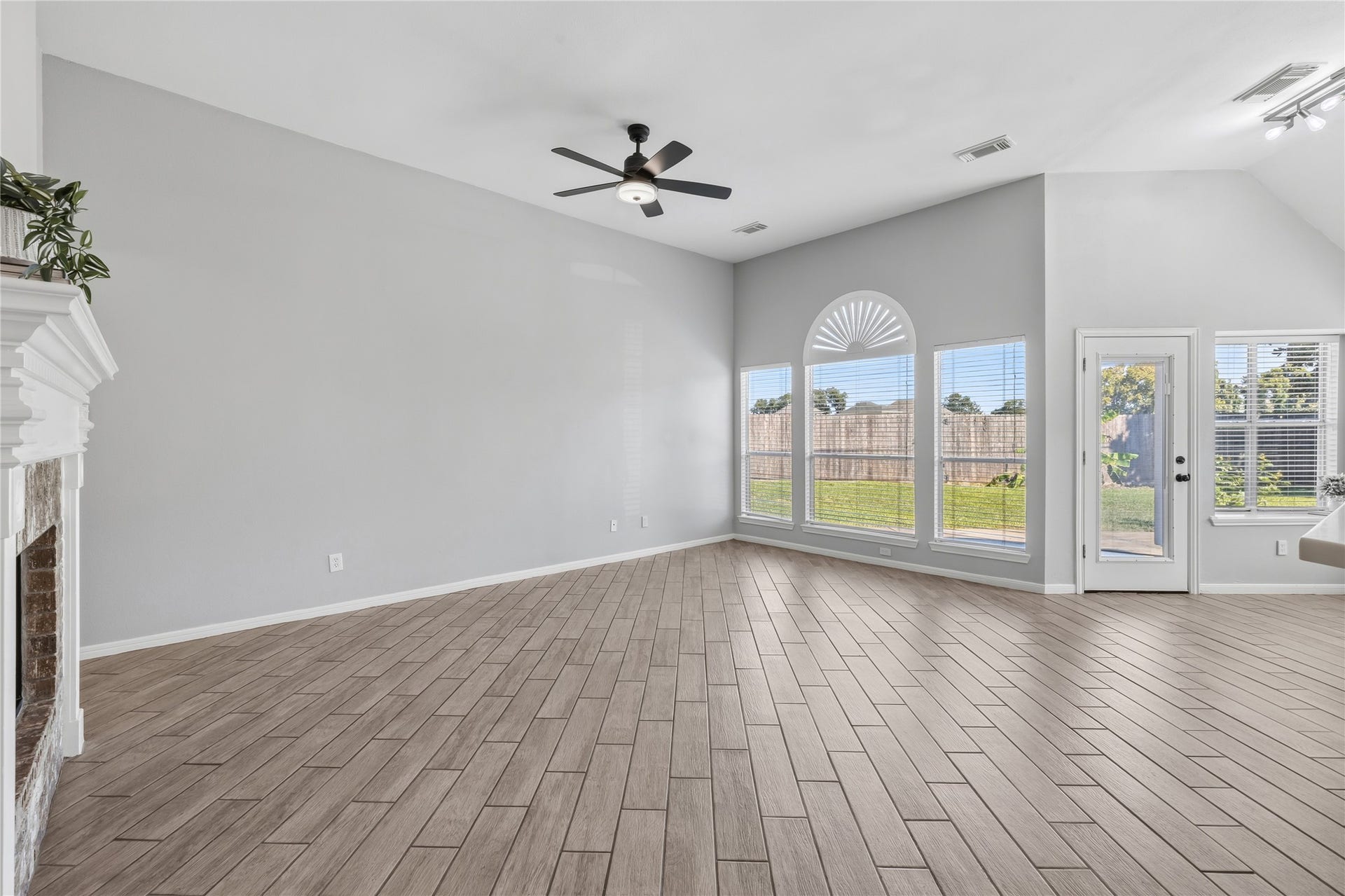 4011 Grayson Court, Missouri City, TX 77459 Spacious living area with elegant wood-look tile flooring, high ceilings, and abundant natural light from large windows overlooking the backyard.