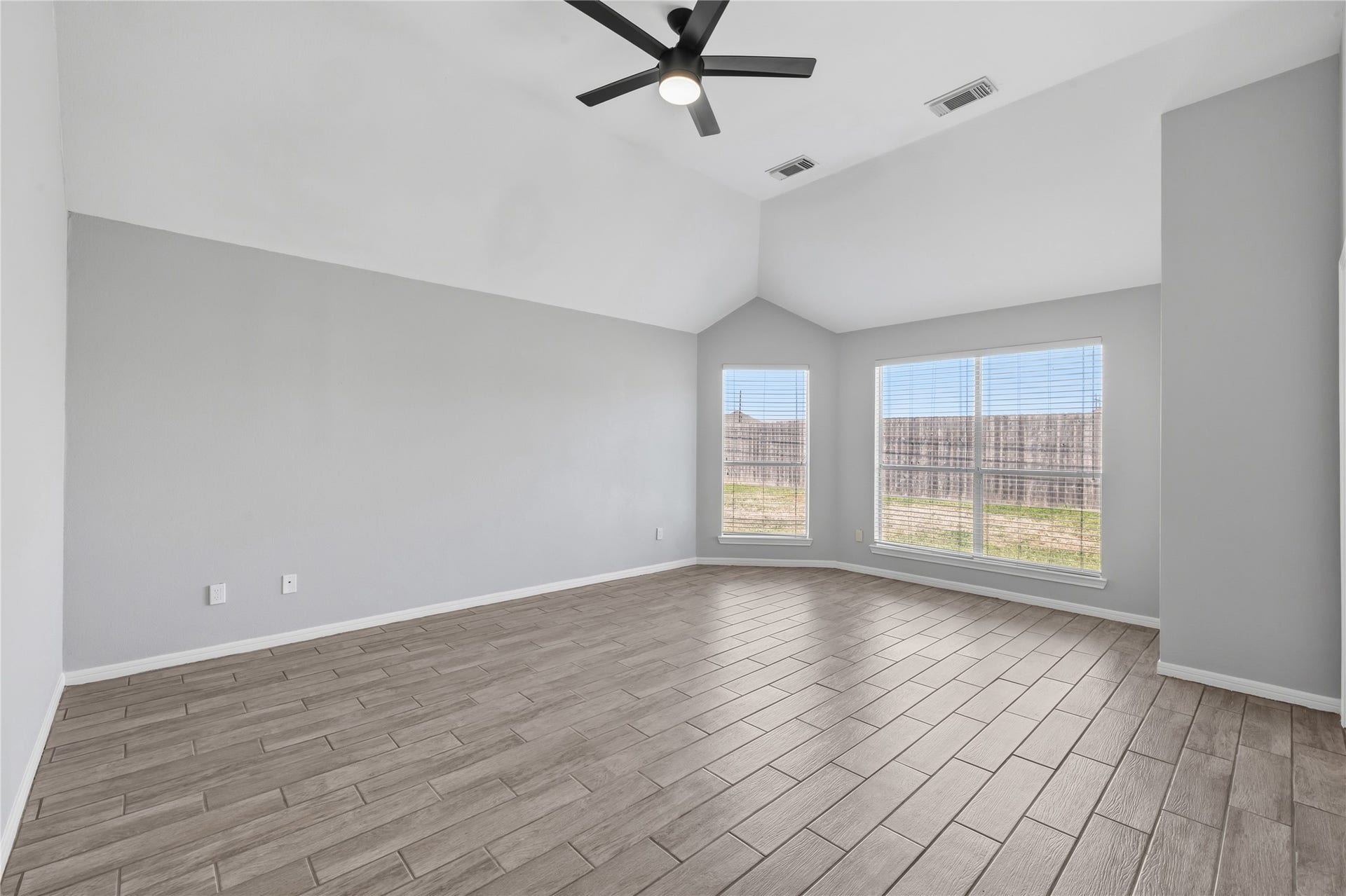 4011 Grayson Court, Missouri City, TX 77459 Primary bedroom with high ceilings, sleek tile flooring, large windows offering abundant natural light, and a modern ceiling fan.