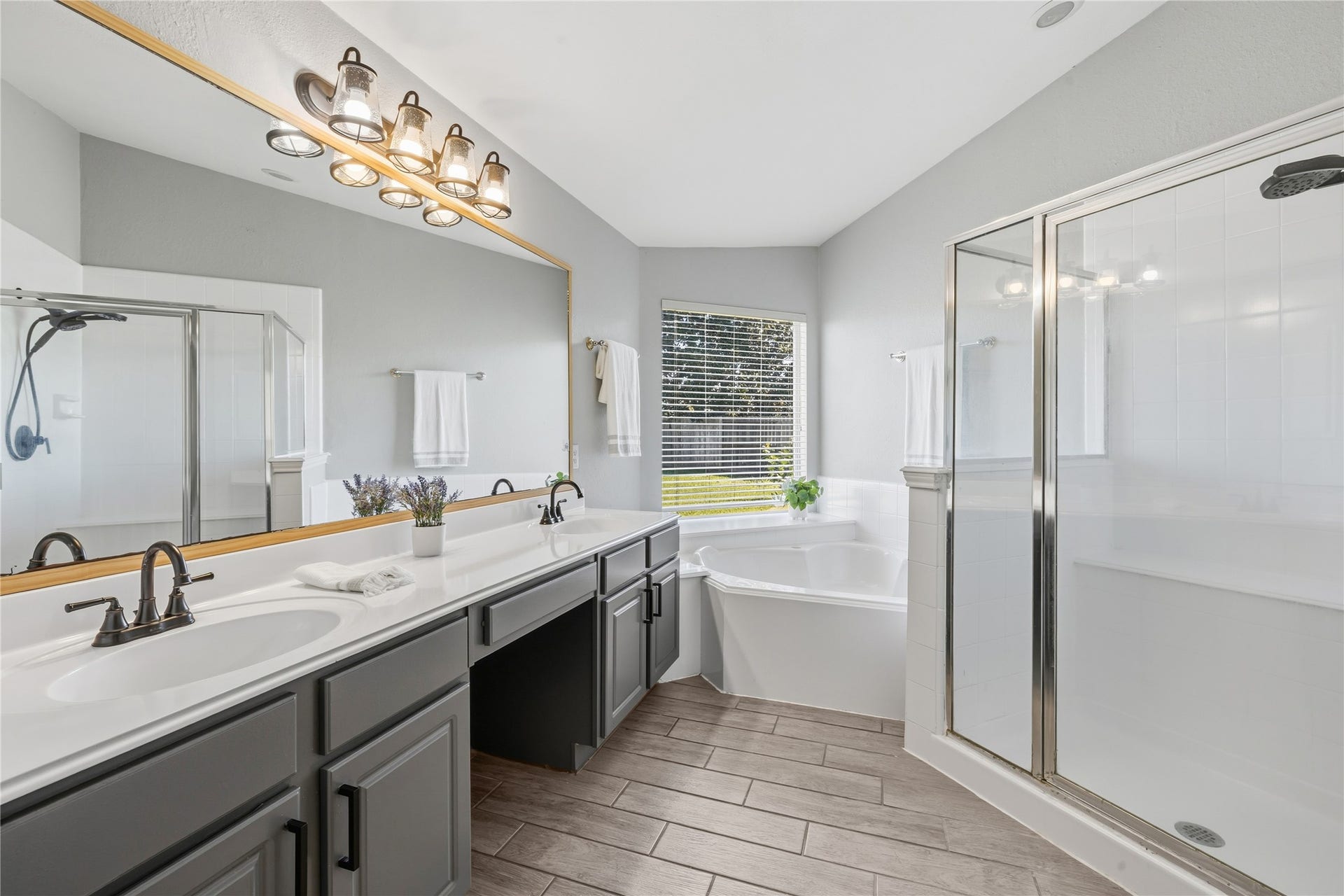 4011 Grayson Court, Missouri City, TX 77459 Primary bathroom featuring a spacious double vanity, sleek fixtures, a large glass-enclosed shower, and a relaxing corner bathtub with natural light streaming through the window.