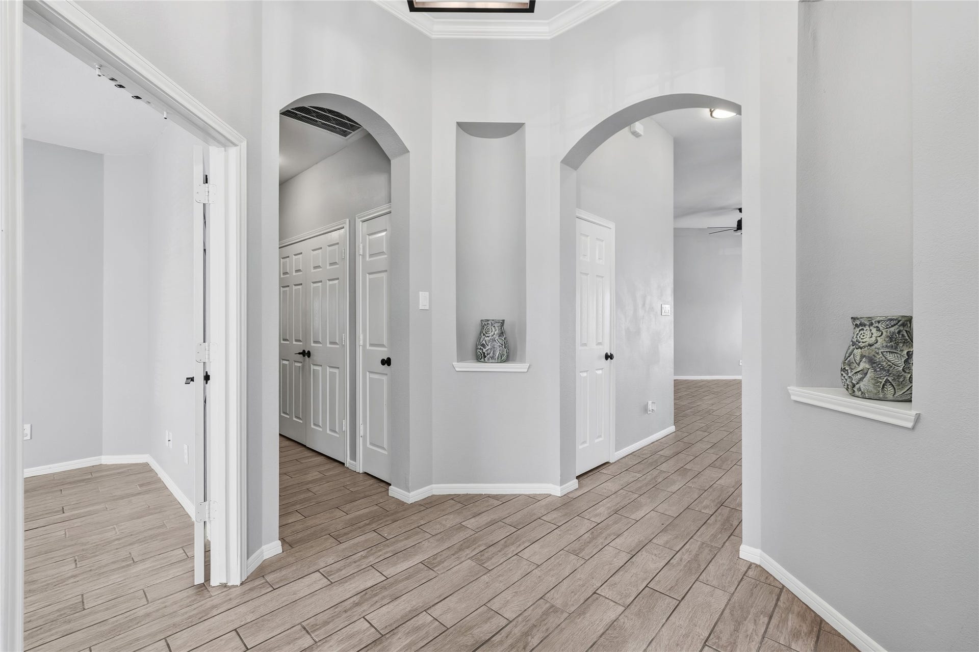 4011 Grayson Court, Missouri City, TX 77459 Elegant entryway featuring arched doorways, neutral tones, and wood-look tile flooring, creating a welcoming and stylish ambiance.