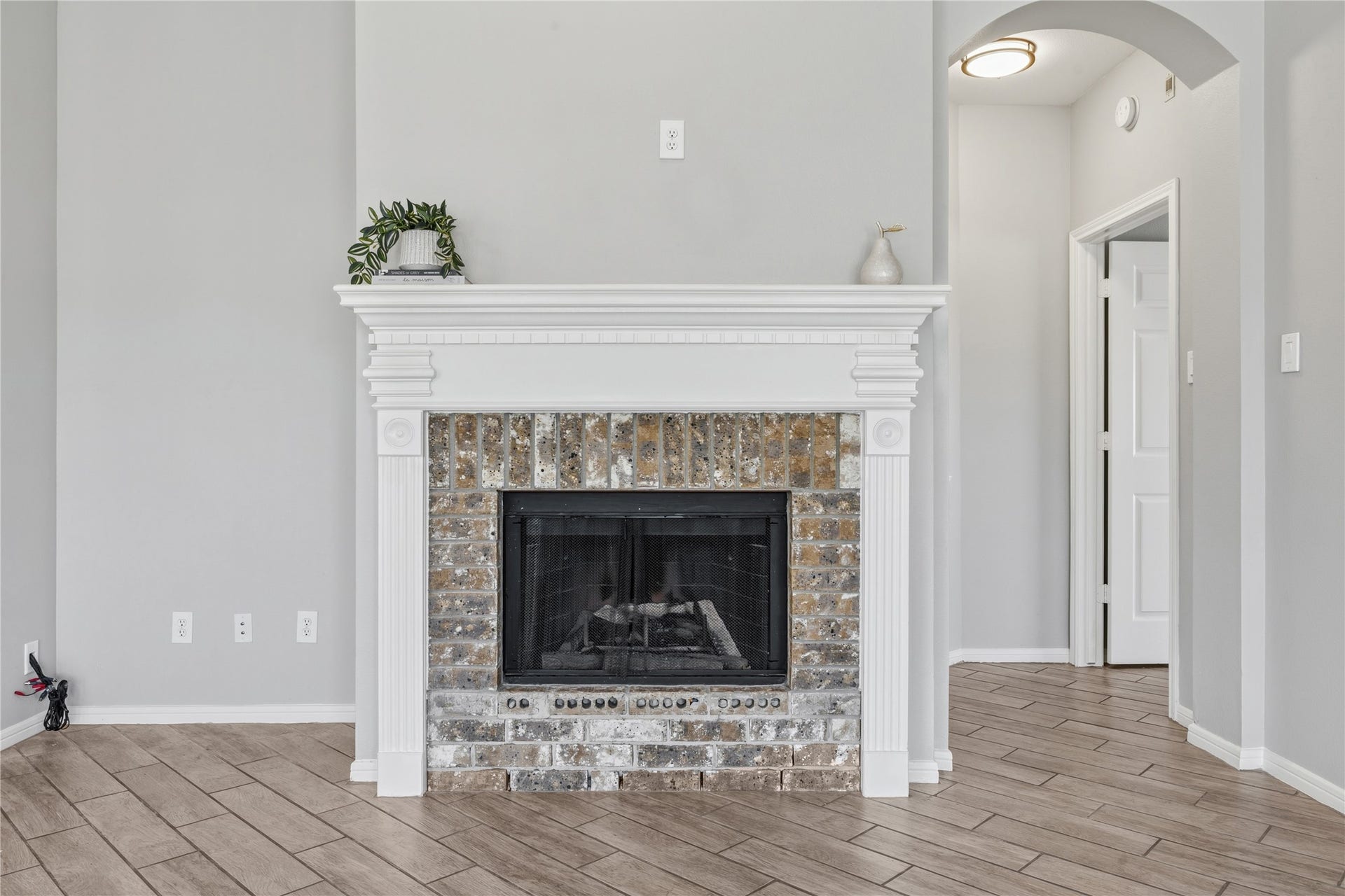 4011 Grayson Court, Missouri City, TX 77459 Charming living room features a classic brick fireplace with a decorative white mantel, set against sleek tile flooring and neutral walls for a cozy, elegant atmosphere.