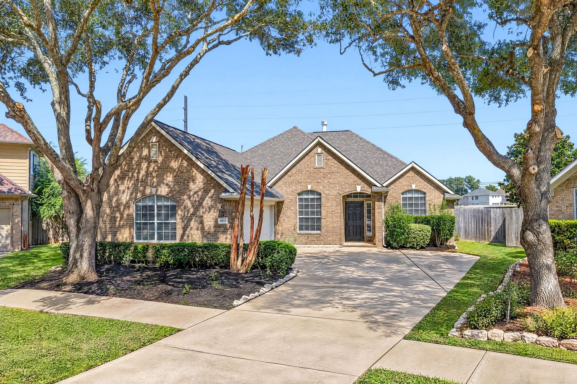 4011 Grayson Court, Missouri City, TX 77459 Charming brick home with a welcoming front entrance, framed by mature trees and manicured landscaping, offering a spacious driveway and excellent curb appeal.