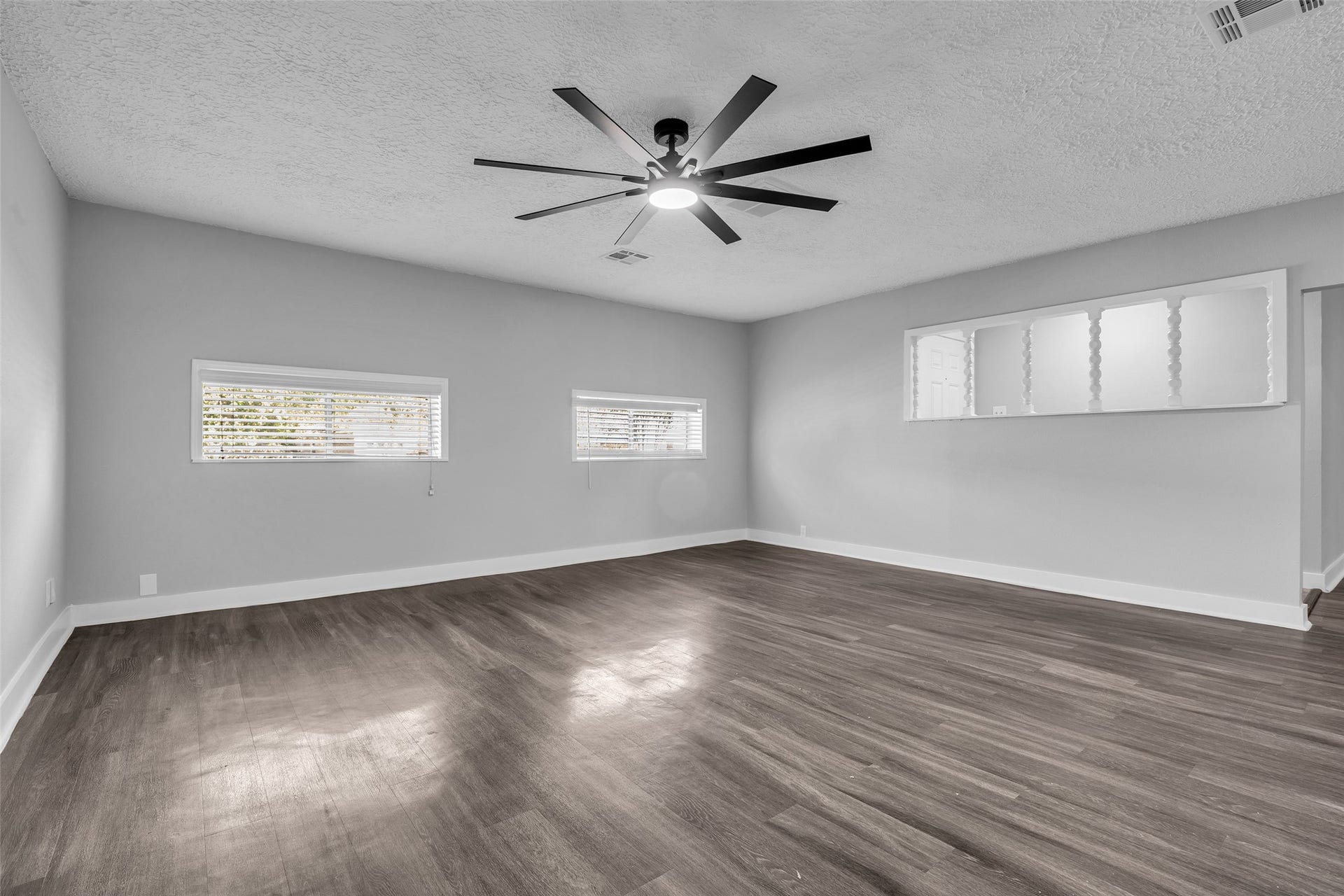 Room to spread out, with natural light from two windows and wood-look plank flooring.