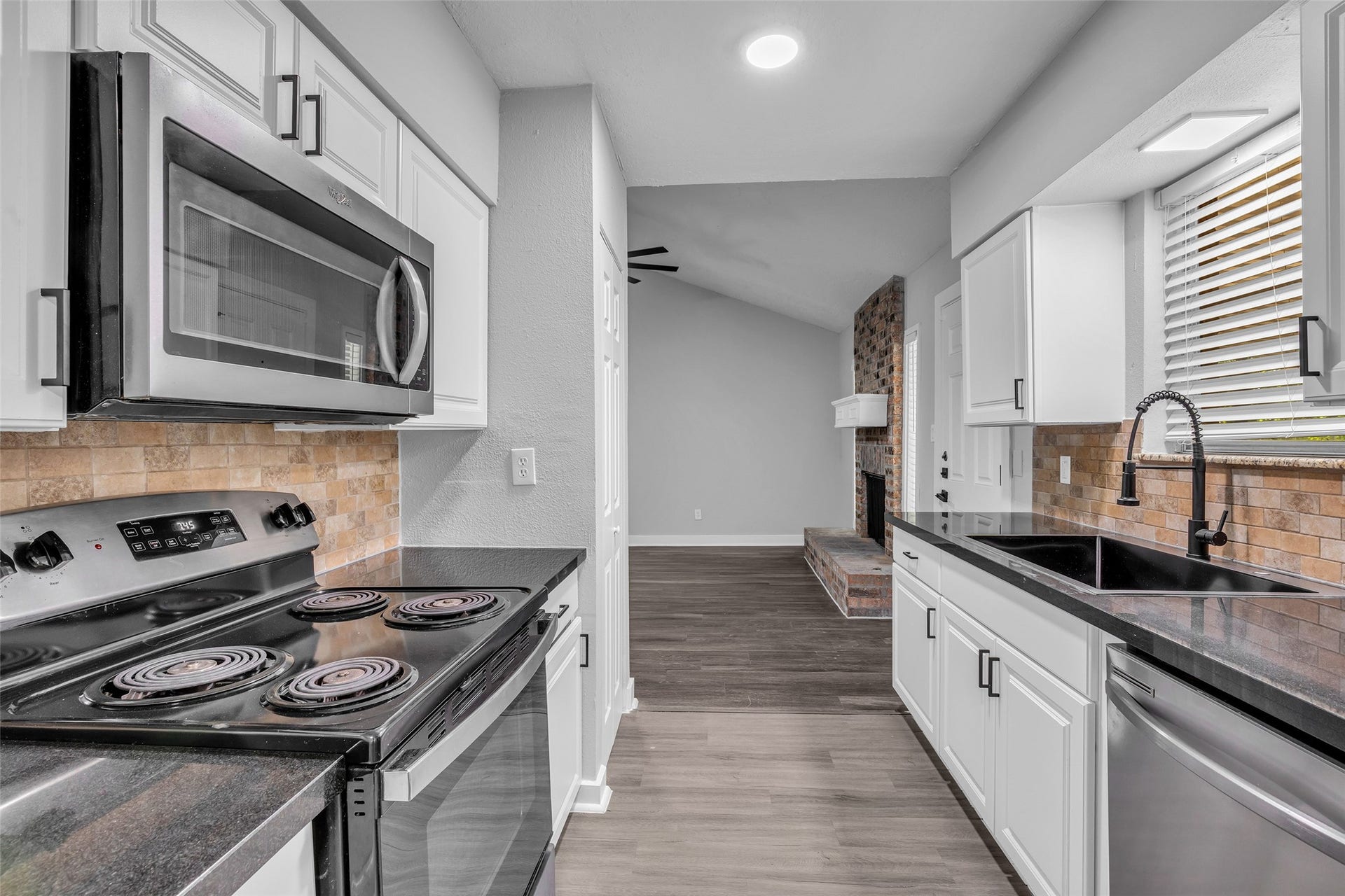 Cook on the electric range with an over-the-range microwave, with a view through to the living room.
