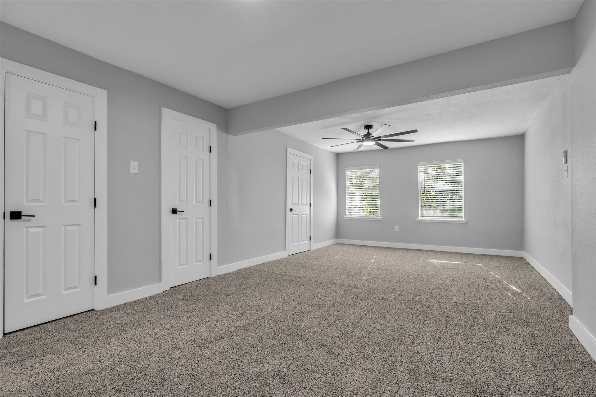 Retreat to a spacious primary bedroom with plush carpet, a ceiling fan and multiple closets.