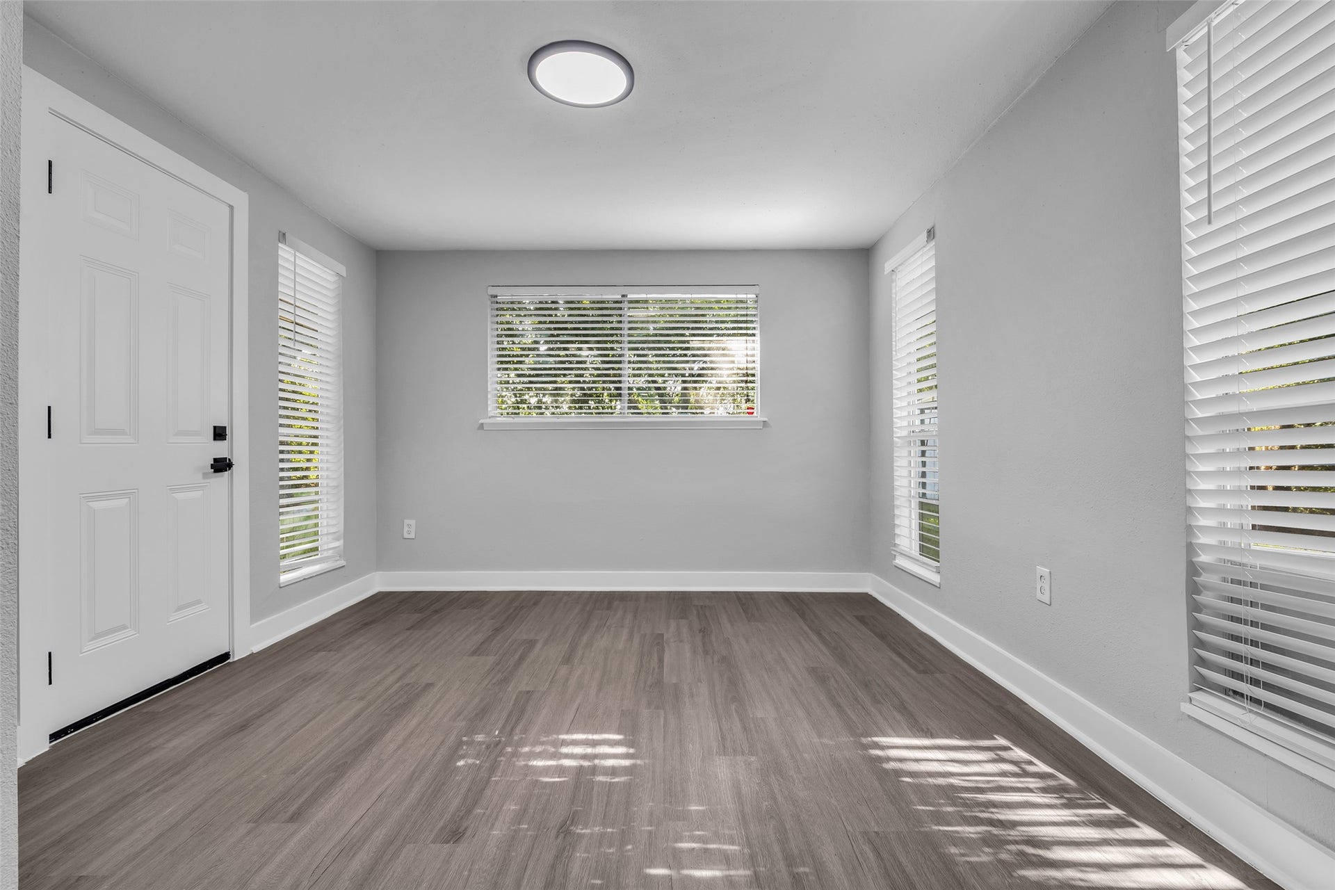 Host dinners in a bright dining area with windows on three sides and a door to the backyard.