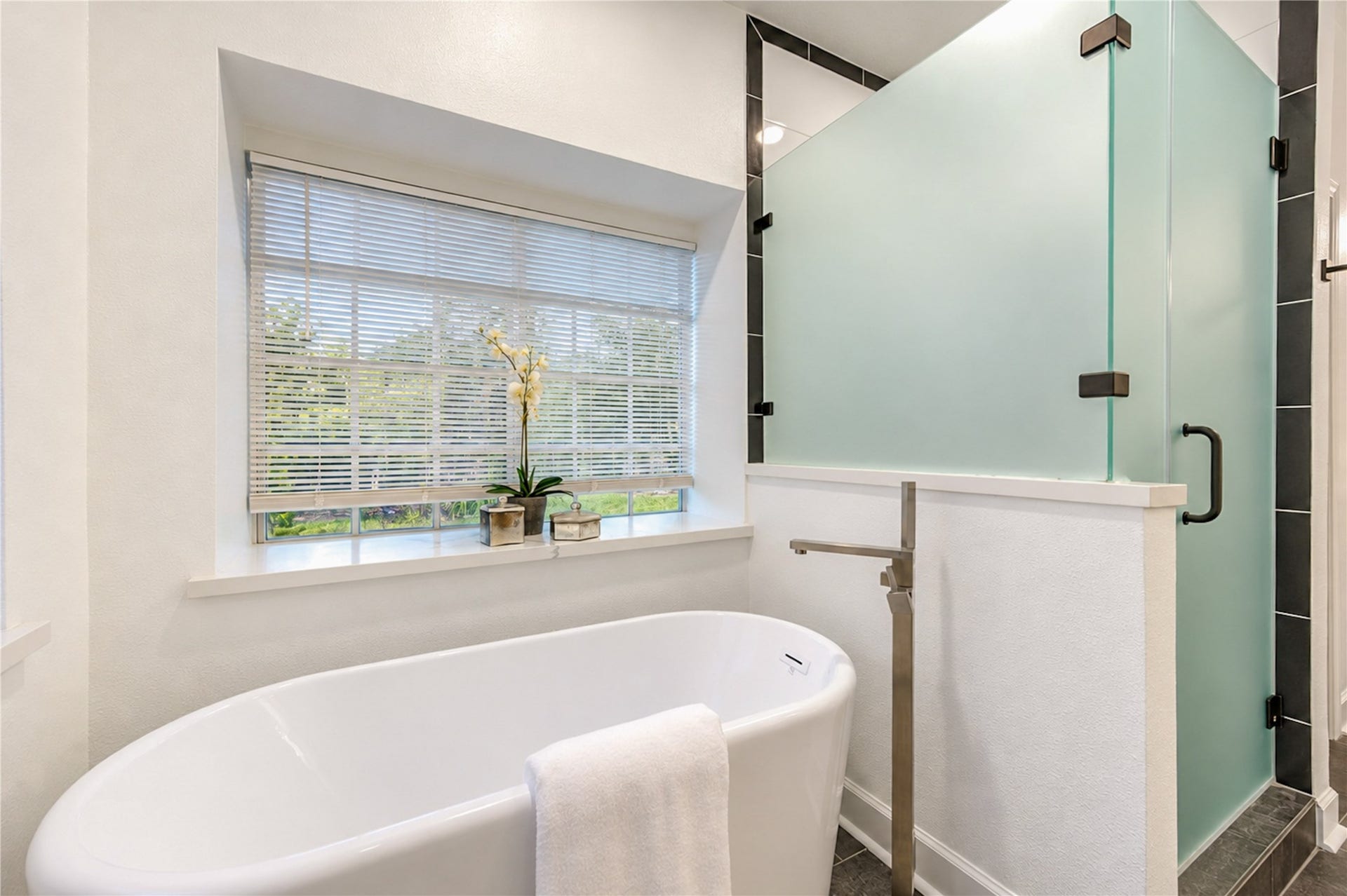 14215 Edinburgh Court, Houston, TX 77077 Your own spa-inspired escape awaits! Soak away the stresses of the day in the elegant freestanding tub or refresh in the spacious glass-enclosed walk-in shower. Beautiful natural light and peaceful views of the greenery outside create the perfect atmosphere for relaxation and everyday indulgence.