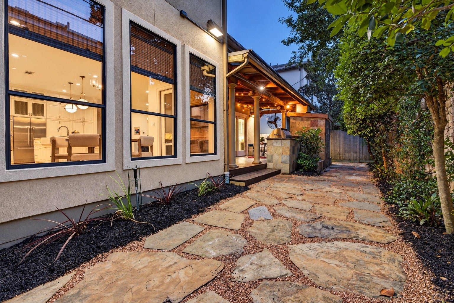 4420 Darsey Street, Bellaire, TX 77401 A stone-paved backyard walkway with a mosquito misting system follows the home's large windows and leads toward the covered entertaining area.
