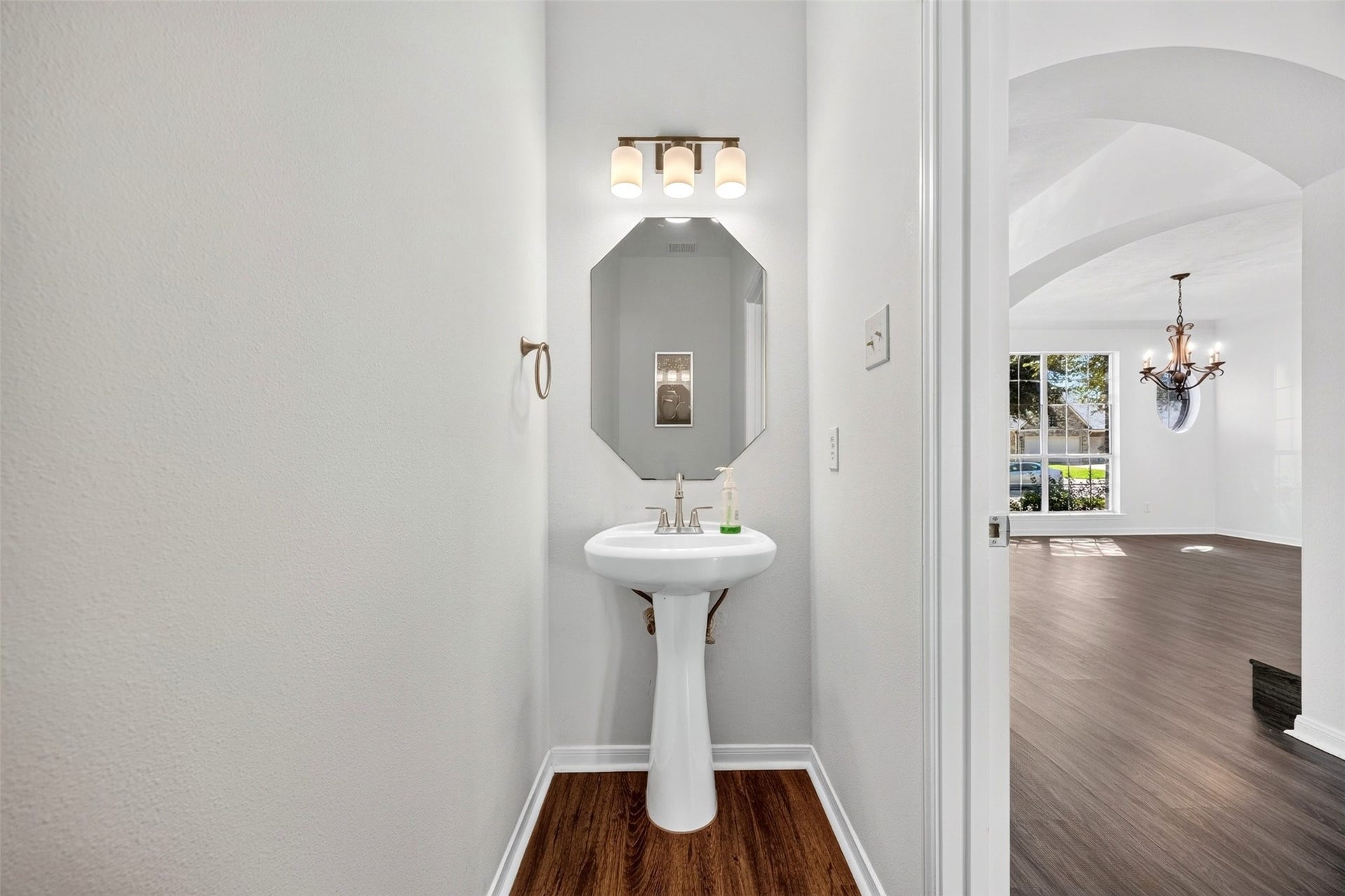3114 Brannon Hill Lane, Sugar Land, TX 77479 Charming powder room with a sleek pedestal sink, elegant lighting, and a modern octagonal mirror