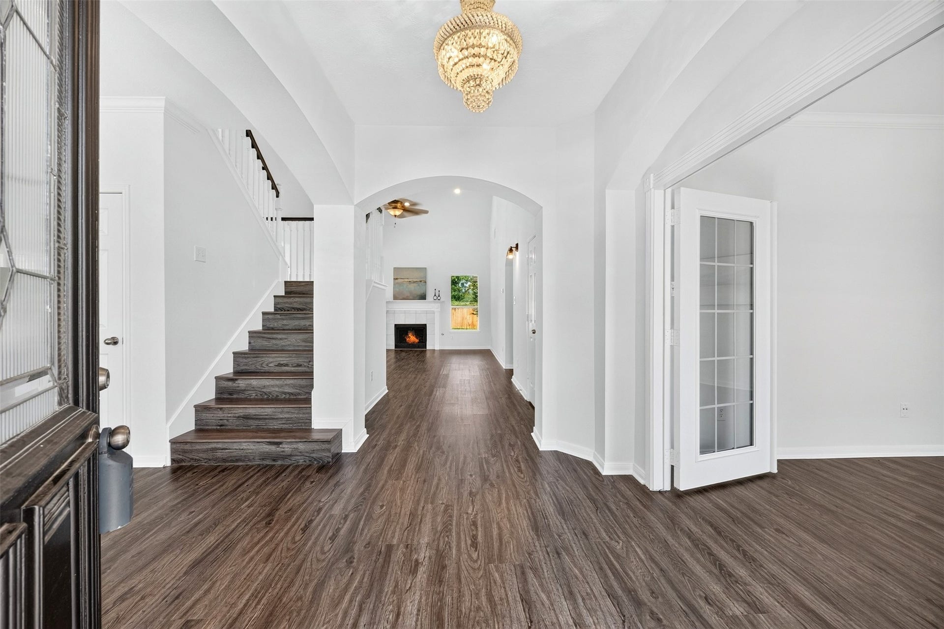 3114 Brannon Hill Lane, Sugar Land, TX 77479 Elegant entryway featuring luxury vinyl plank flooring, a stunning chandelier, and a welcoming staircase leading to the upper level. The open floor plan seamlessly connects to a cozy living area with a fireplace, creating an inviting atmosphere.