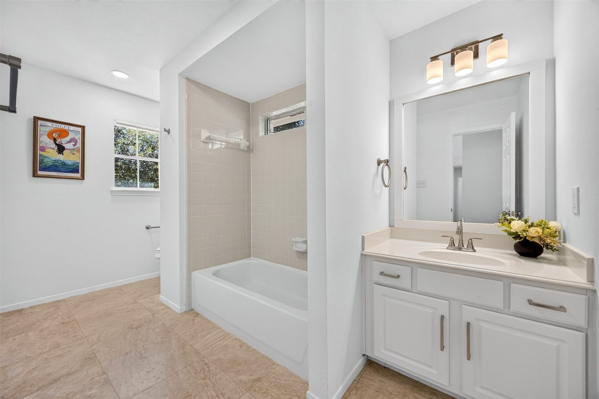 3114 Brannon Hill Lane, Sugar Land, TX 77479 Bright and inviting bathroom featuring a modern vanity with ample storage, a classic bathtub, and elegant tile flooring, enhanced by natural light from the window.