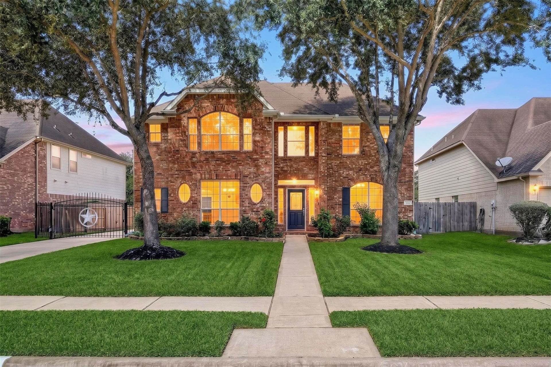 3114 Brannon Hill Lane, Sugar Land, TX 77479 Charming two-story brick home with large, illuminated windows and a welcoming front entrance, nestled in a beautifully landscaped yard with mature trees.