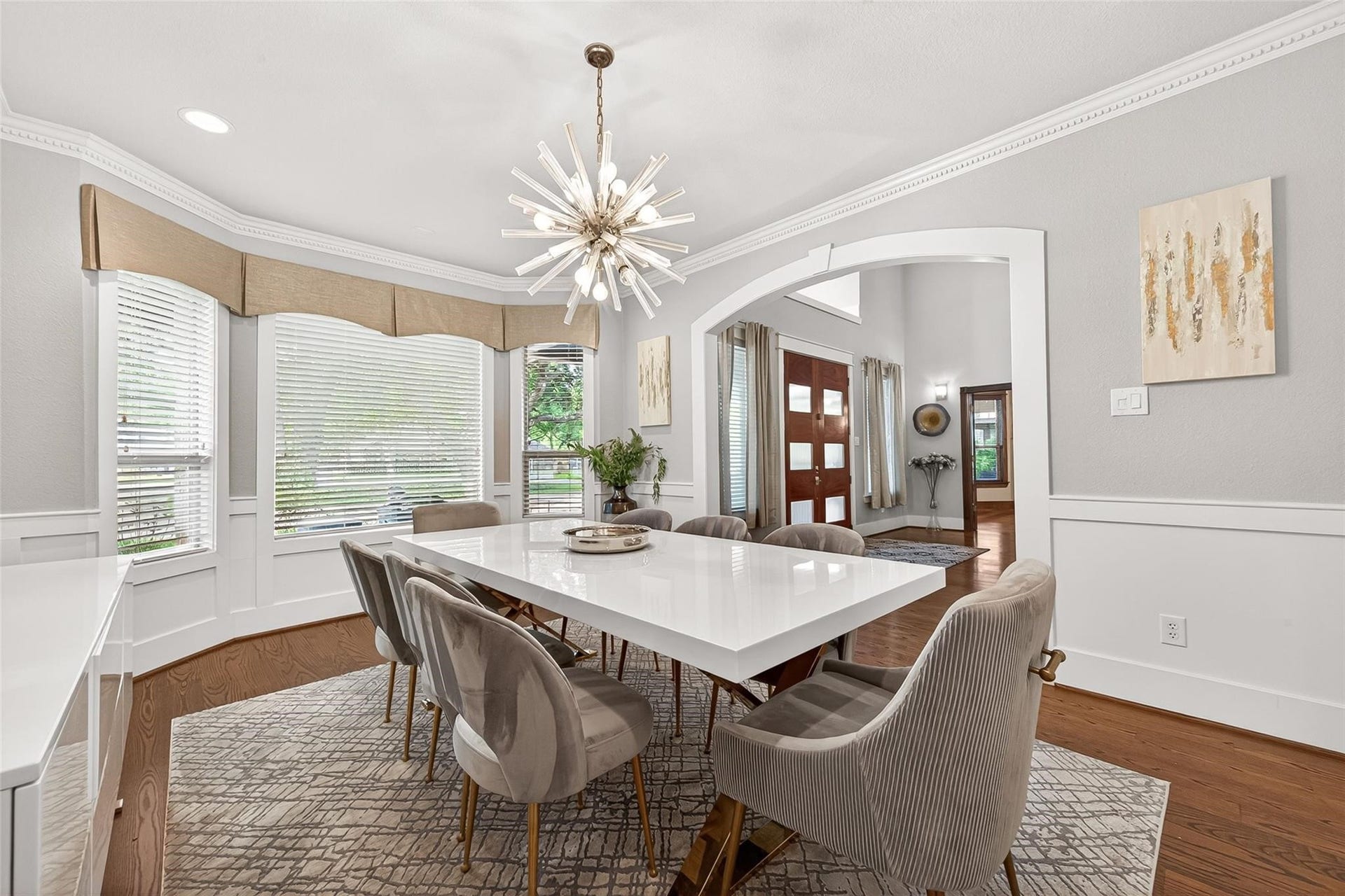 Formal dining room with custom window coverings, modern fixture, light and bright throughout