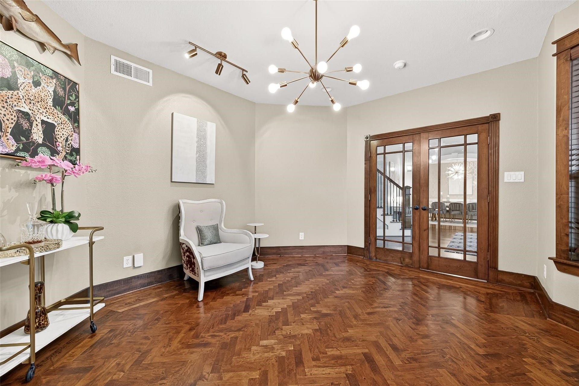 The office boasts custom built-in cabinets, herringbone hardwood flooring, and abundance of natural light from the front yard.