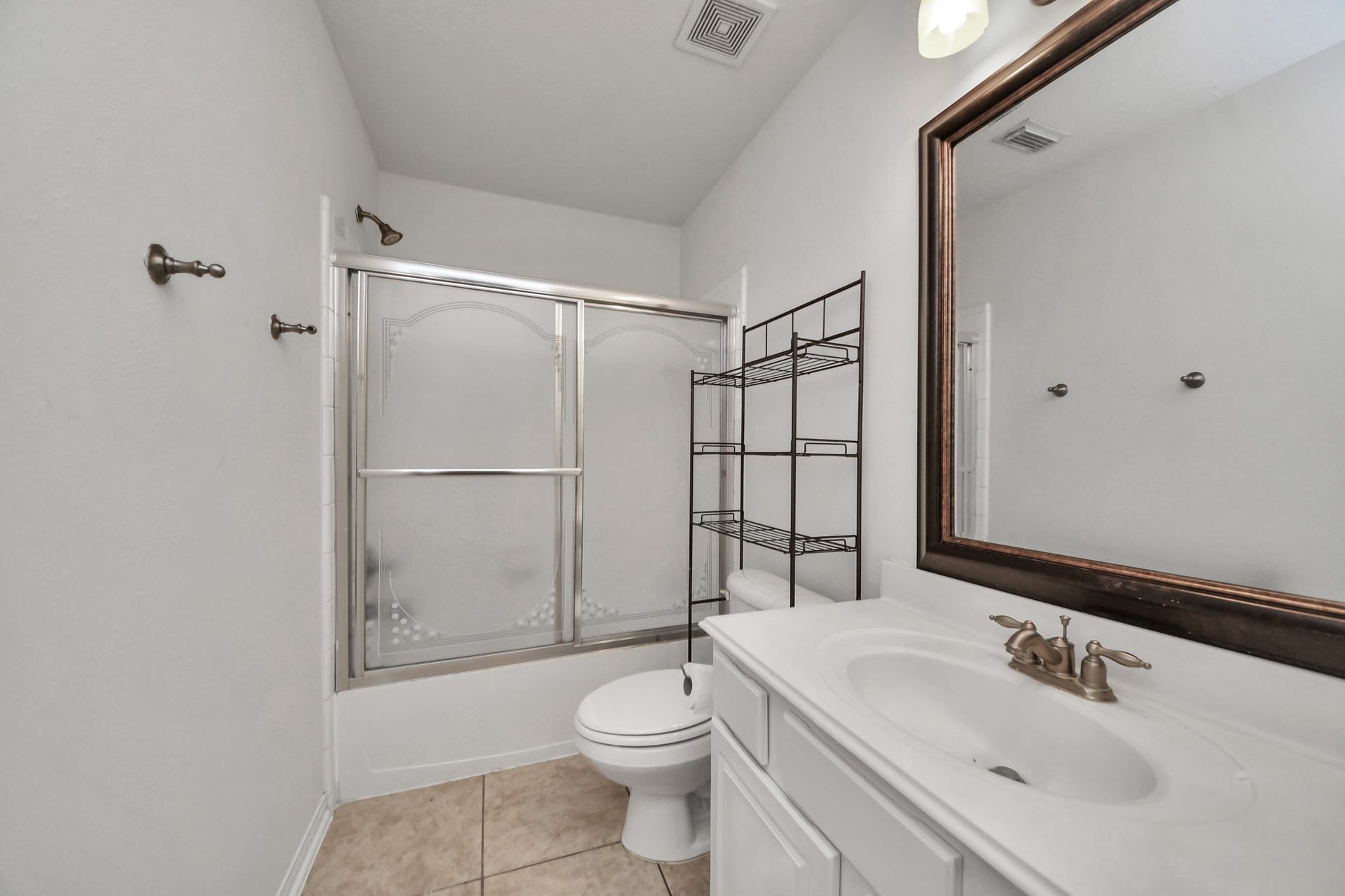 Bright and functional bathroom featuring a sleek shower-tub combo, elegant vanity with ample storage, and a spacious mirror for a modern touch.