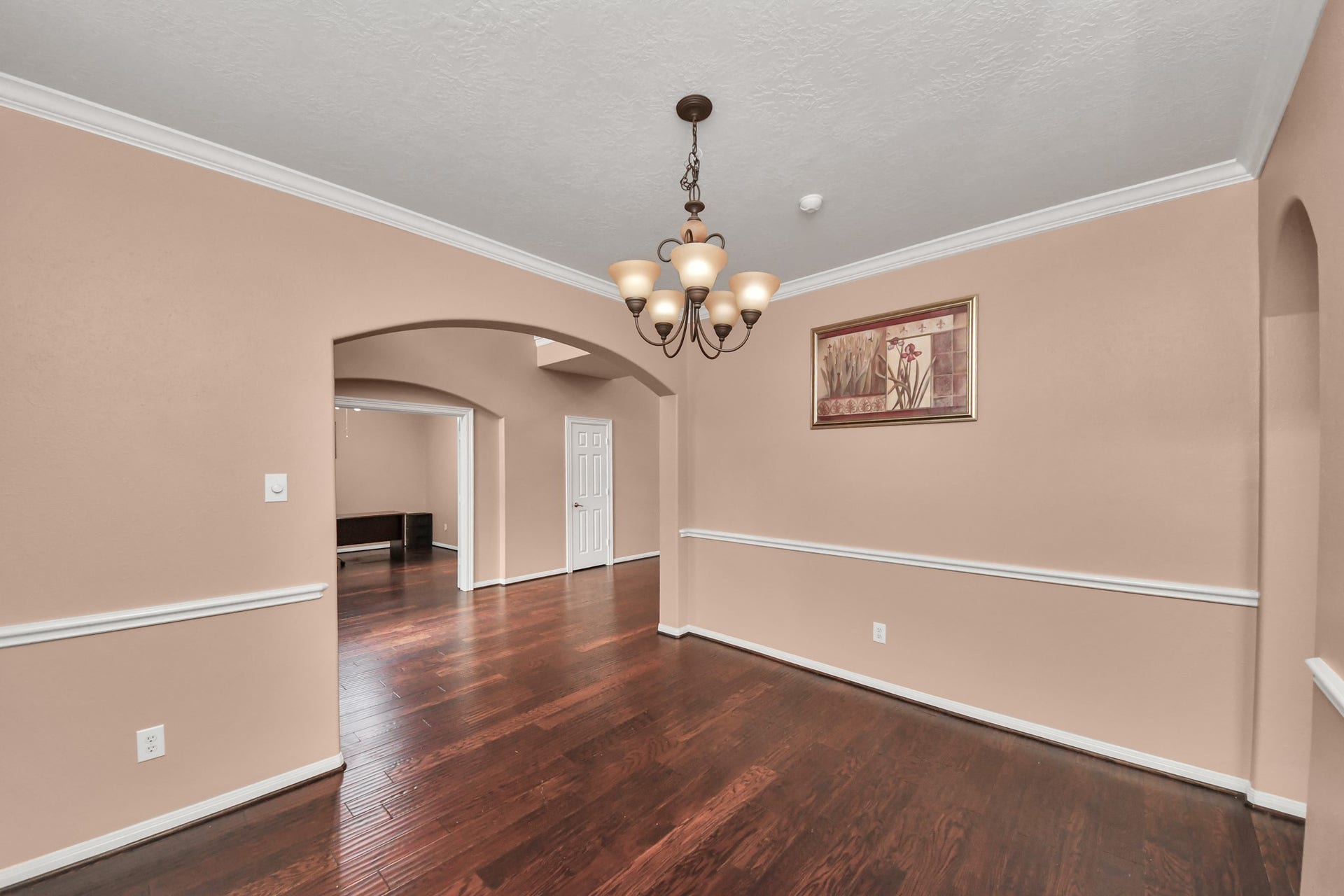 Elegant dining room with rich hardwood floors, crown molding, and a classic chandelier, offering a stylish setting for gatherings.