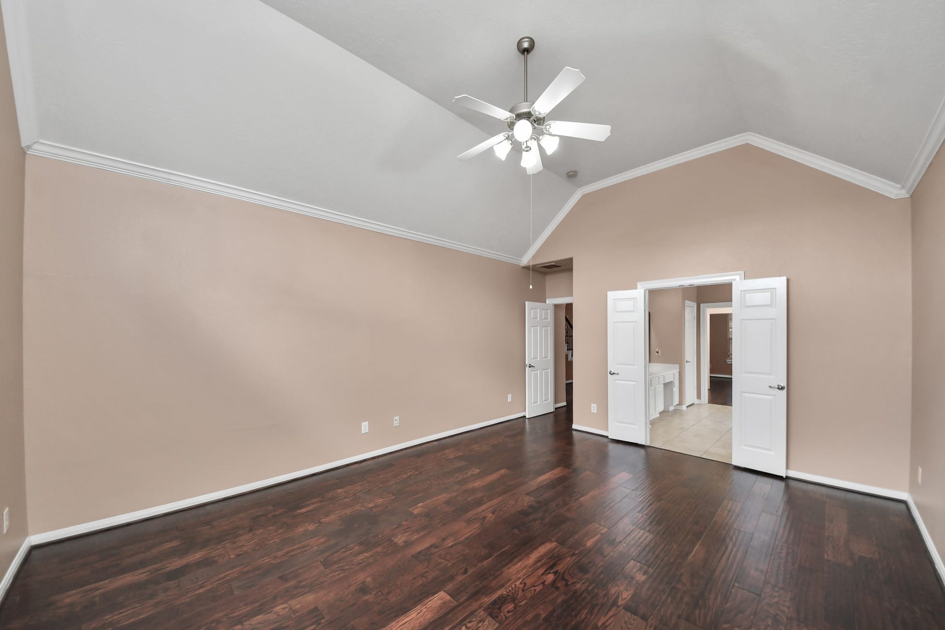 Spacious room with high vaulted ceilings, elegant hardwood floors, and a ceiling fan, offering a bright and airy atmosphere.