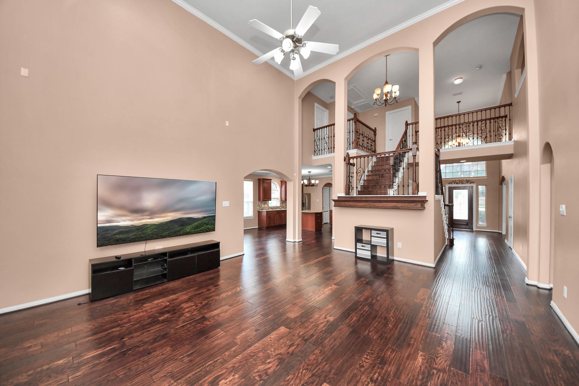 Stunning open-concept living space with high ceilings, elegant wood flooring, and a grand staircase, offering a blend of luxury and comfort perfect for entertaining.