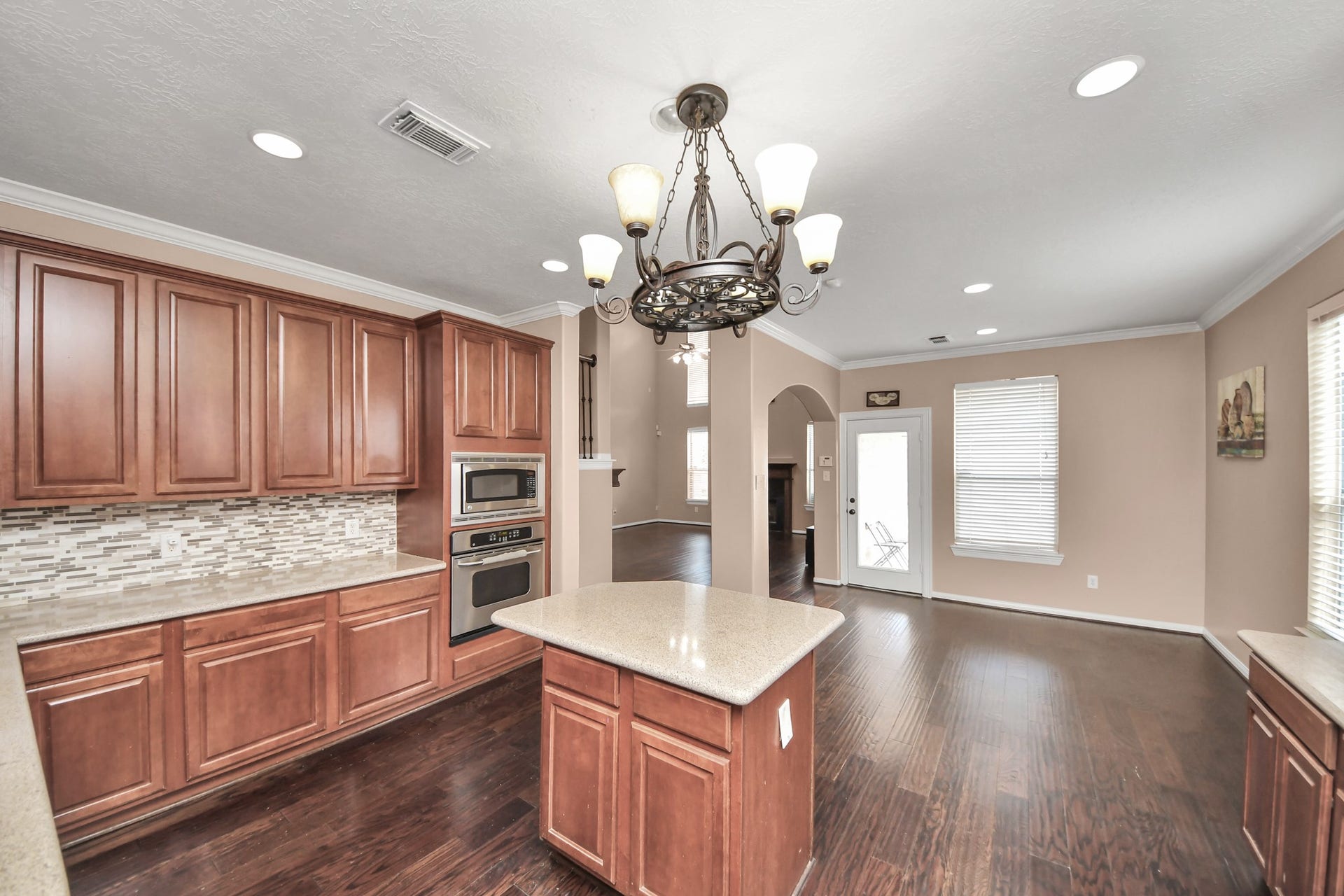 Spacious kitchen with elegant wood cabinetry, a central island, and modern built-in appliances, complemented by a stylish tile backsplash and a cozy breakfast area.