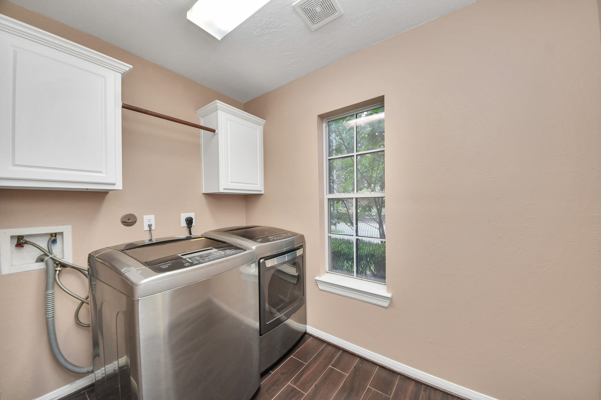 Bright and functional laundry room featuring modern appliances, ample cabinetry, and a large window for natural light.