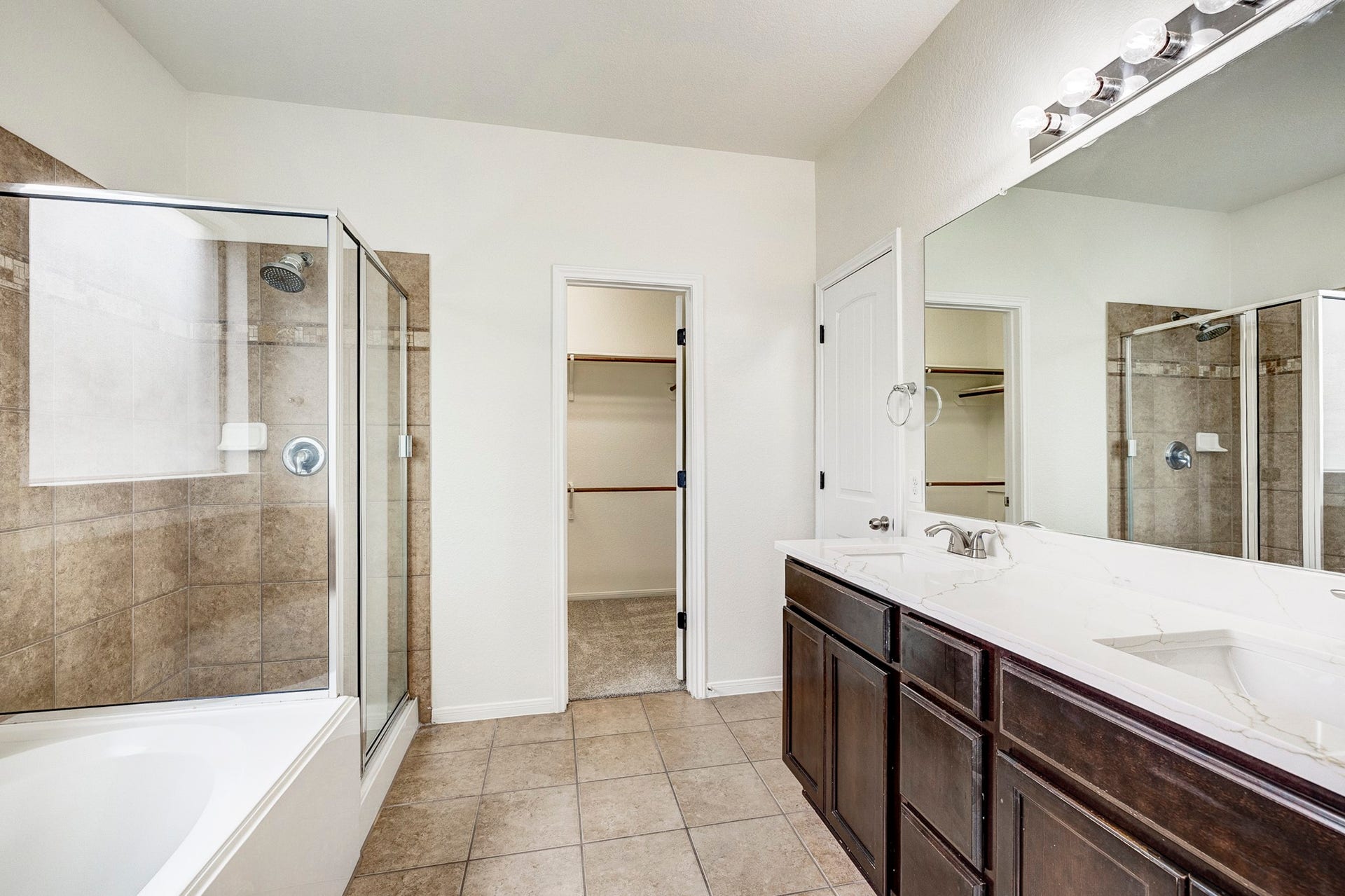 33227 Greenfield Forest Drive, Magnolia, TX 77354 Spacious bathroom featuring a dual-sink vanity, glass-enclosed shower, and a relaxing bathtub, with direct access to a walk-in closet.
