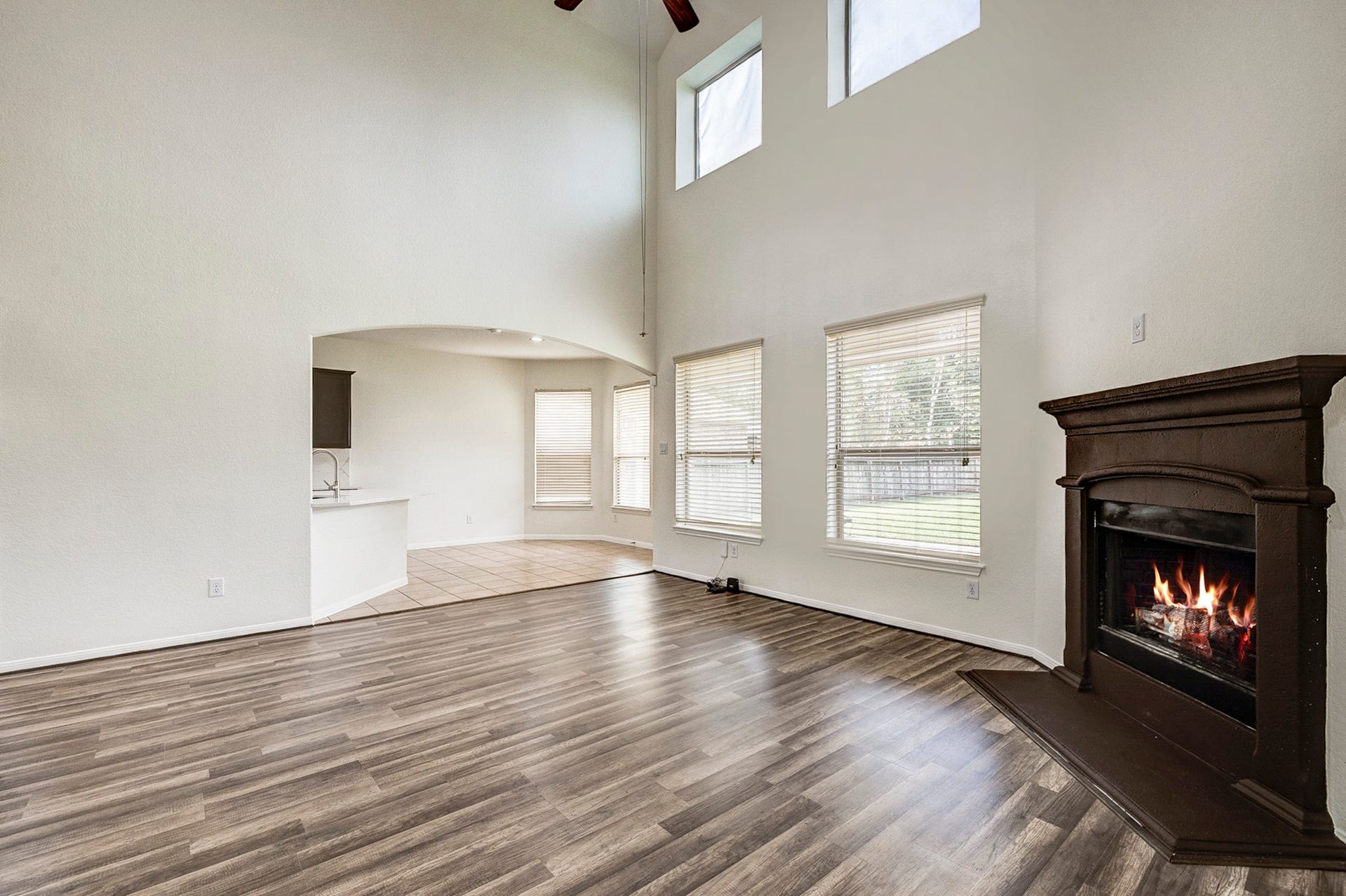 33227 Greenfield Forest Drive, Magnolia, TX 77354 Spacious living area with high ceilings, elegant wood flooring, and a cozy fireplace, seamlessly connecting to a bright dining nook with large windows and an open kitchen.