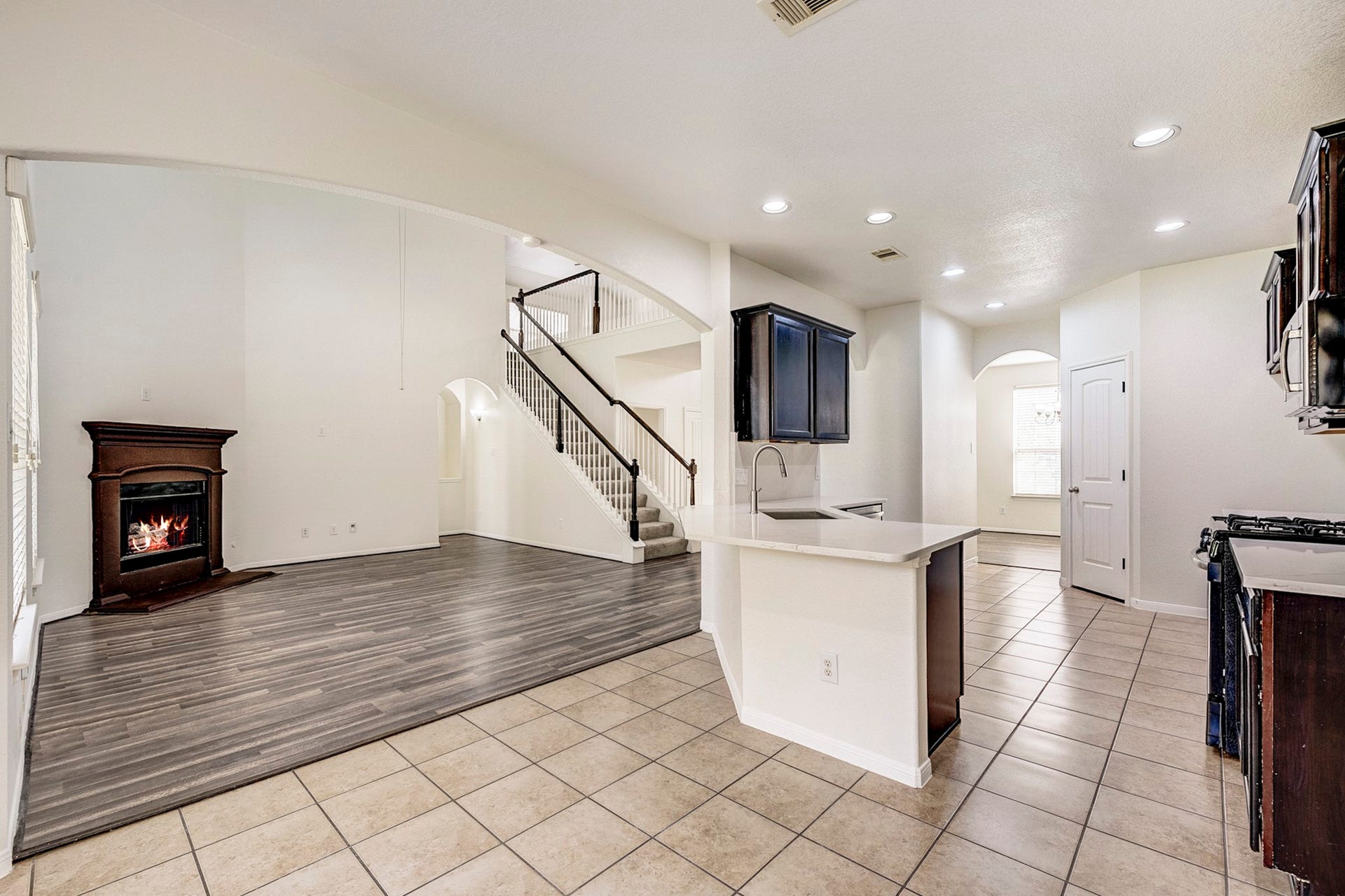33227 Greenfield Forest Drive, Magnolia, TX 77354 Spacious open-concept living area with a cozy fireplace, modern kitchen with an island, and elegant staircase leading to the upper level.