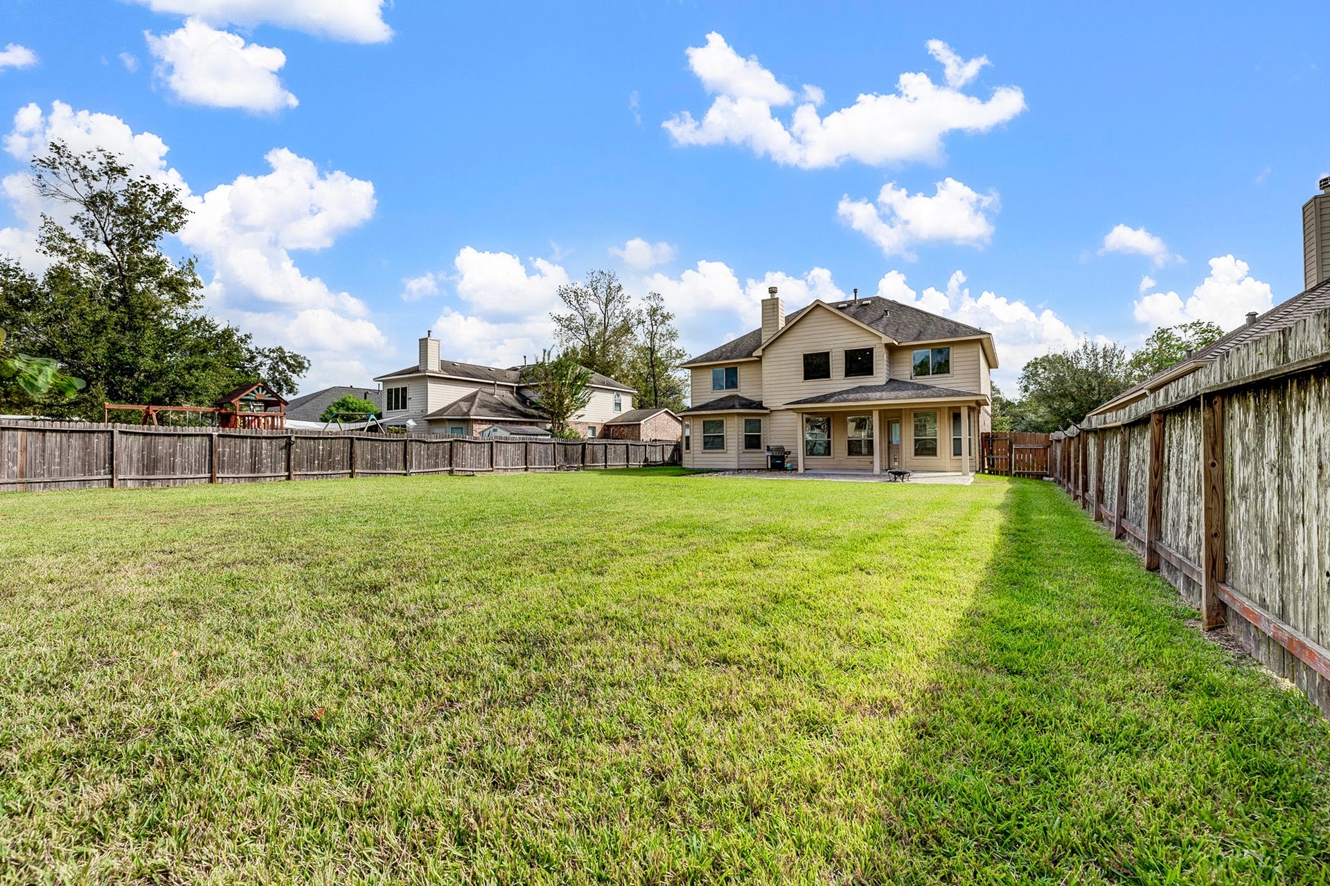 33227 Greenfield Forest Drive, Magnolia, TX 77354 Expansive backyard with lush green lawn and a spacious two-story home, perfect for family gatherings and outdoor activities.