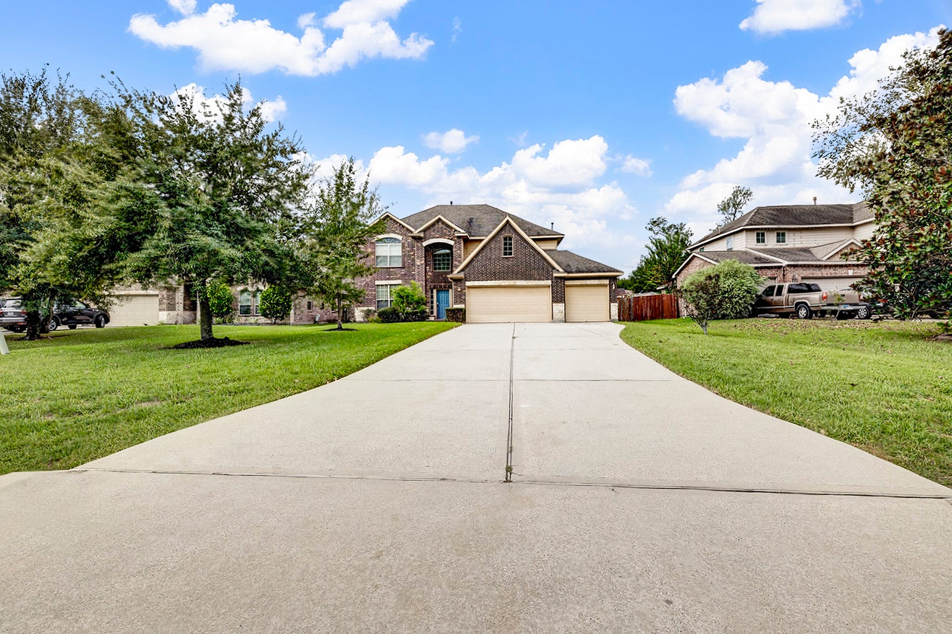 33227 Greenfield Forest Drive, Magnolia, TX 77354 Stunning two-story brick home with a spacious three-car garage, set on a beautifully landscaped lot with a long driveway and mature trees.