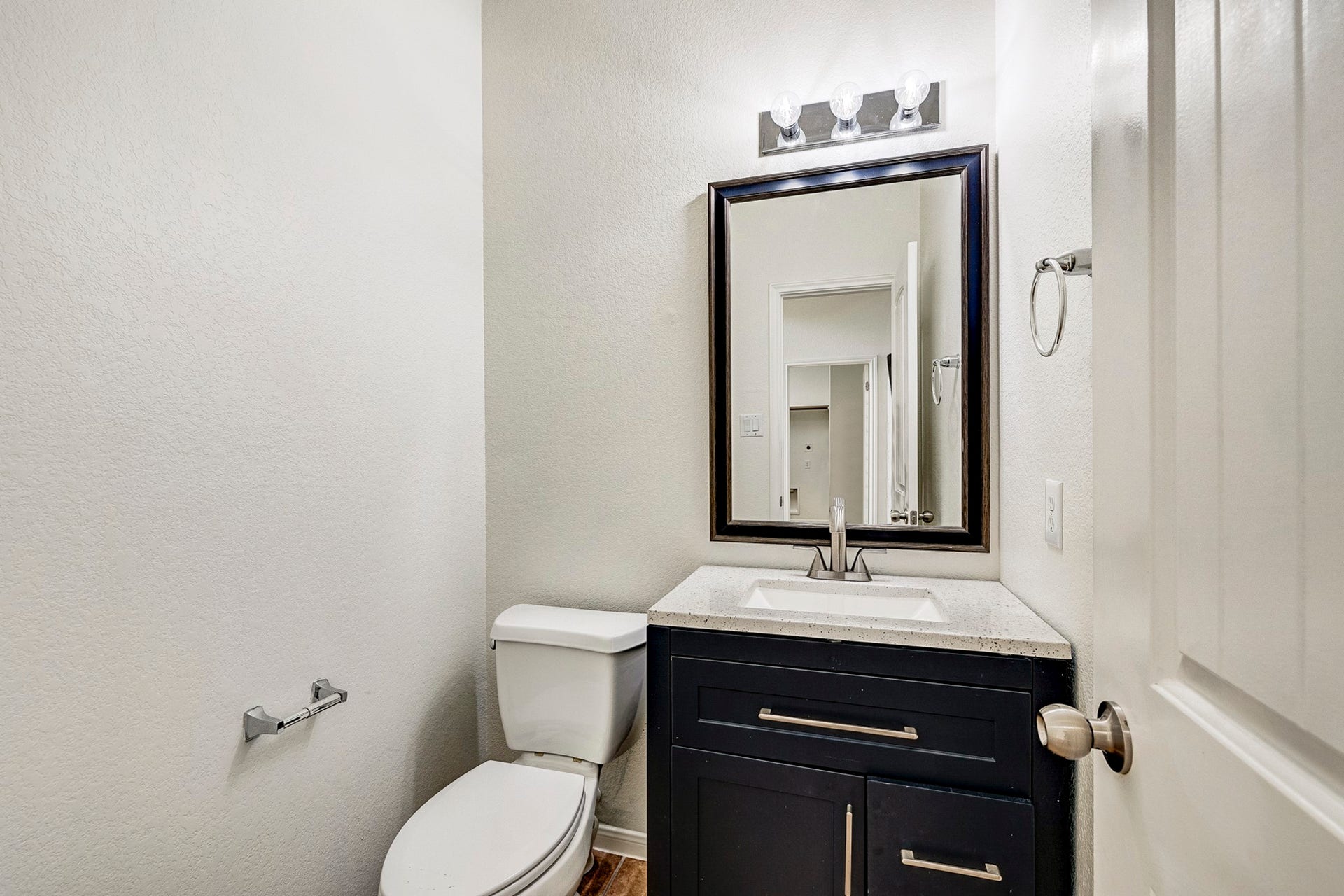 33227 Greenfield Forest Drive, Magnolia, TX 77354 Modern half-bath featuring a sleek vanity with granite countertop, elegant lighting, and a large framed mirror for a touch of sophistication.