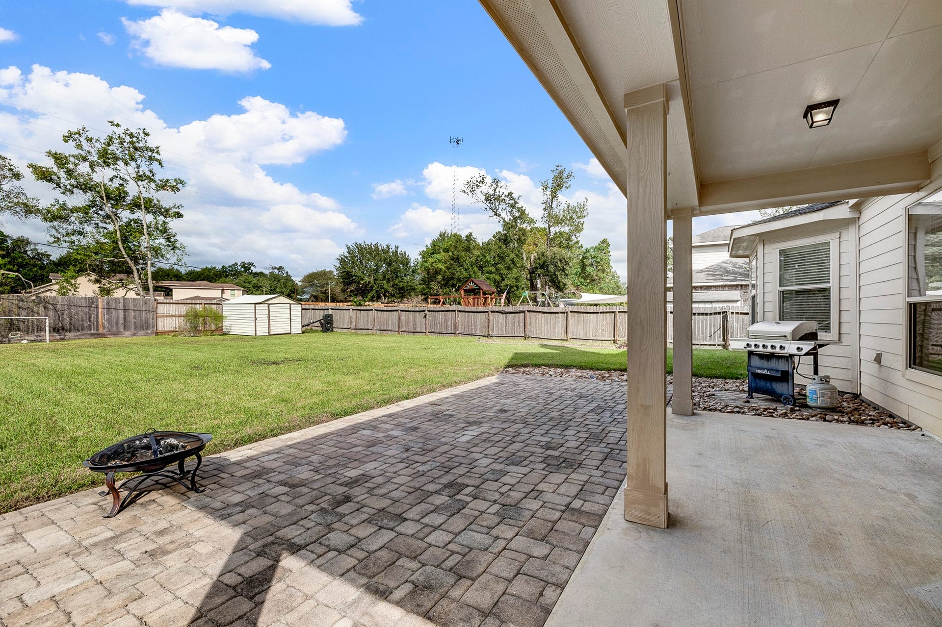 33227 Greenfield Forest Drive, Magnolia, TX 77354 Spacious backyard featuring a covered patio with a grill, perfect for outdoor entertaining, and a large, well-maintained lawn ideal for recreation and relaxation.